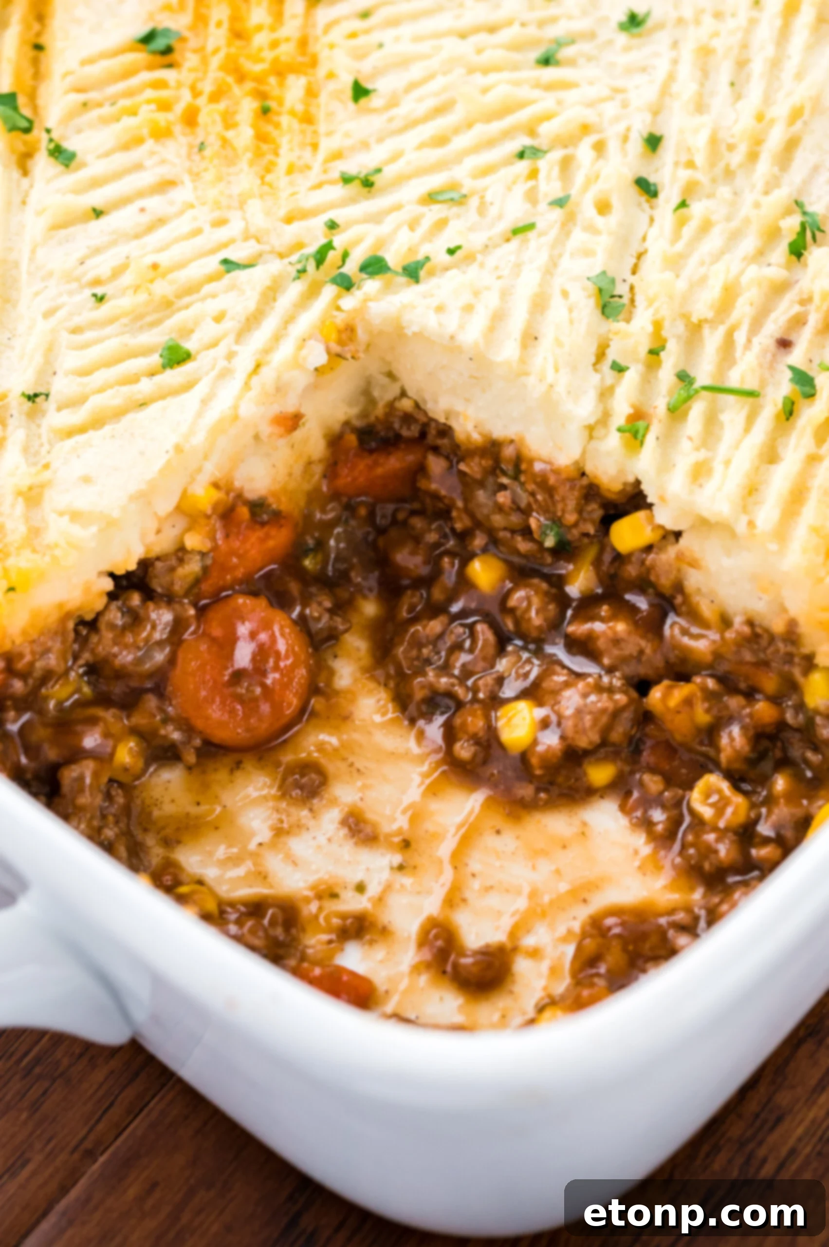 Close up of the Shepherds pie in a white casserole baking dish with a slice removed