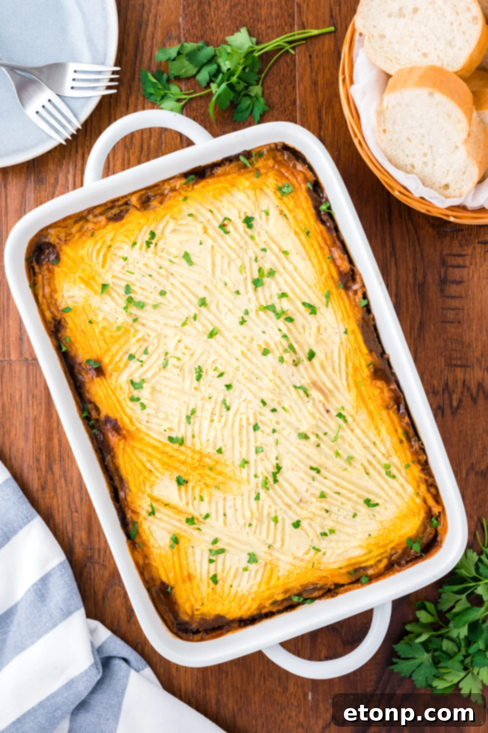 Overhead shot of the baked Shepherd's Pie in a white baking dish topped with chopped parsley. 