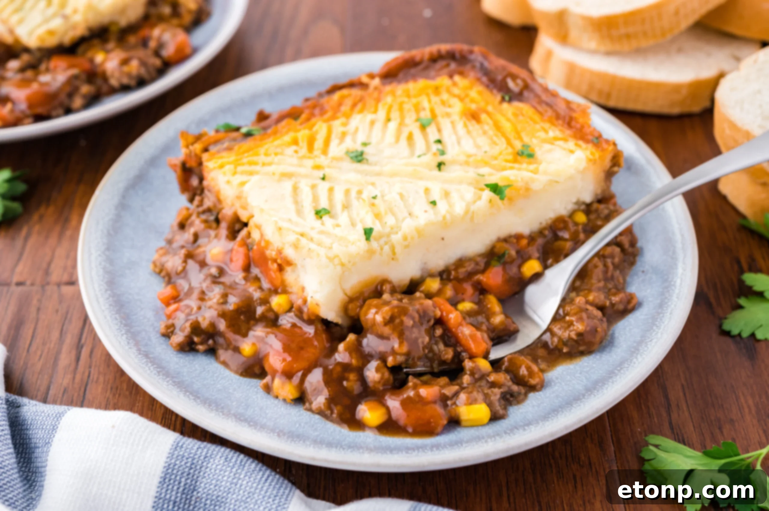 Shepherd's pie on a gray and white plate with a silver fork. 