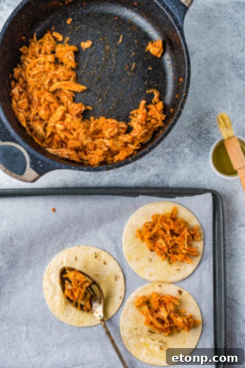 Hand holding a Crispy Tinga Taco, showing its delicious filling.