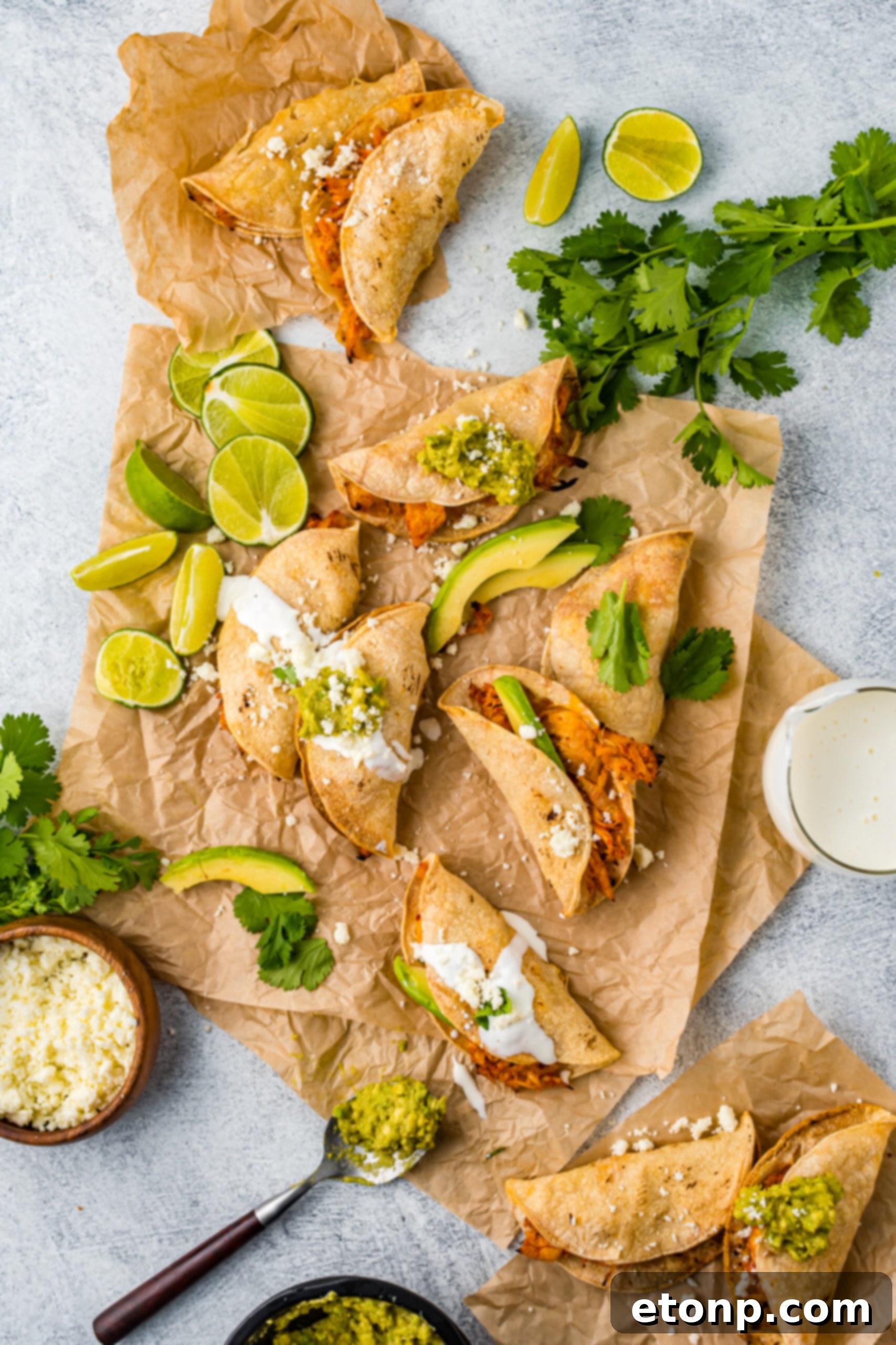 An overhead shot showcasing Crispy Tinga Tacos beautifully arranged on parchment paper, surrounded by bright lime slices and creamy avocado, ready to be enjoyed.