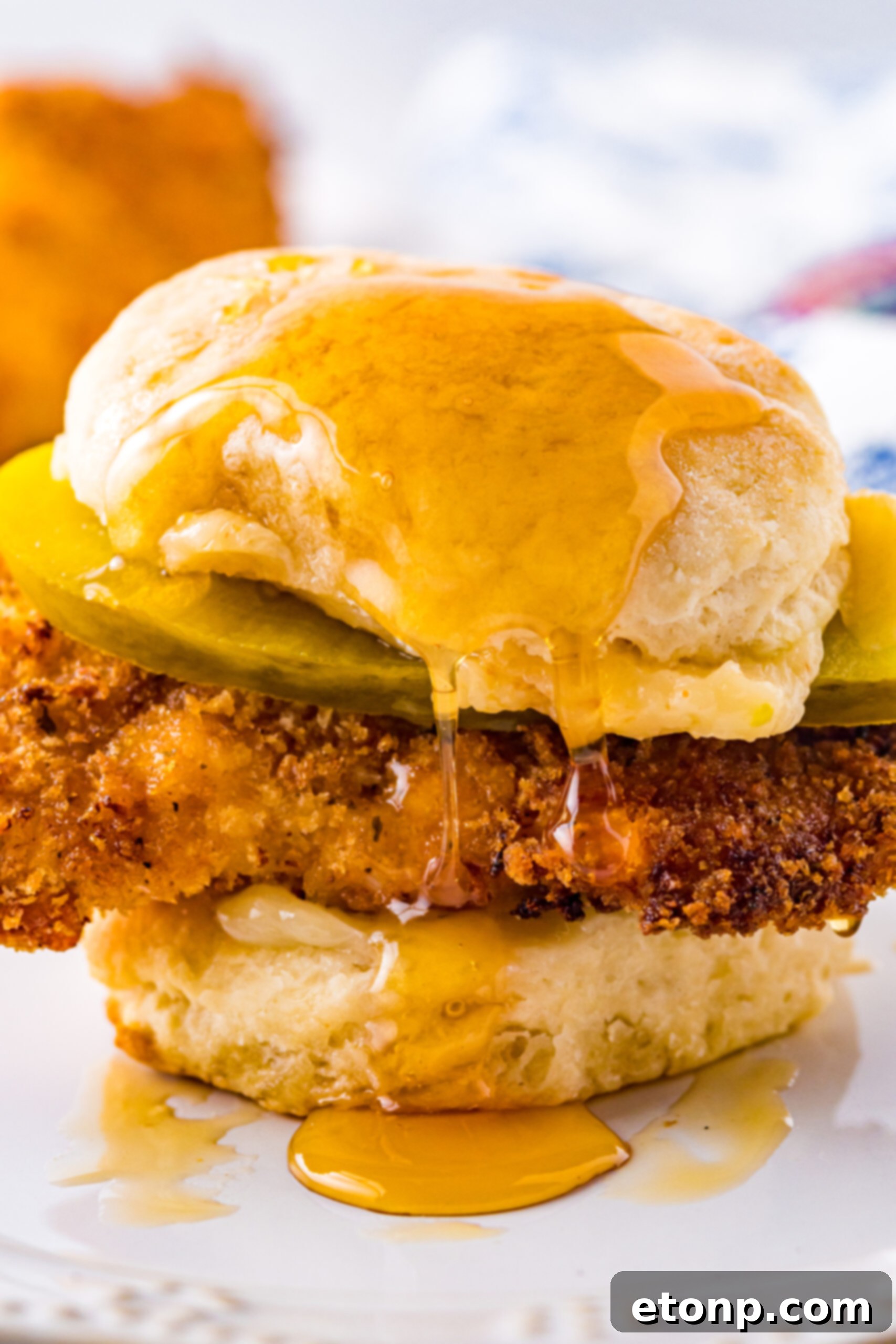Front view of a delicious Honey Butter Chicken Biscuit on a white plate, ready to be enjoyed.