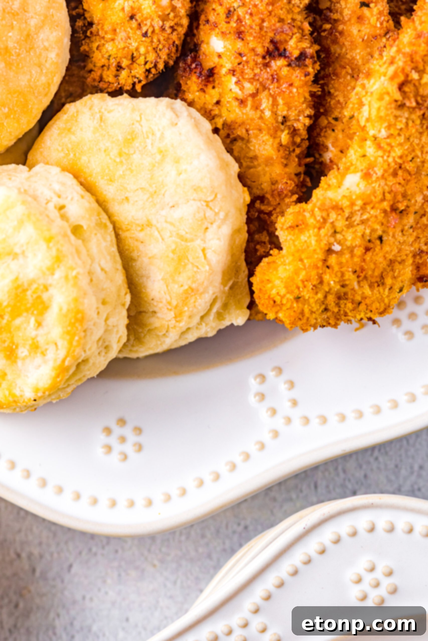 Close-up view of Honey Butter Chicken Biscuit unassembled, highlighting the golden crispy texture of the chicken and the flaky biscuit.