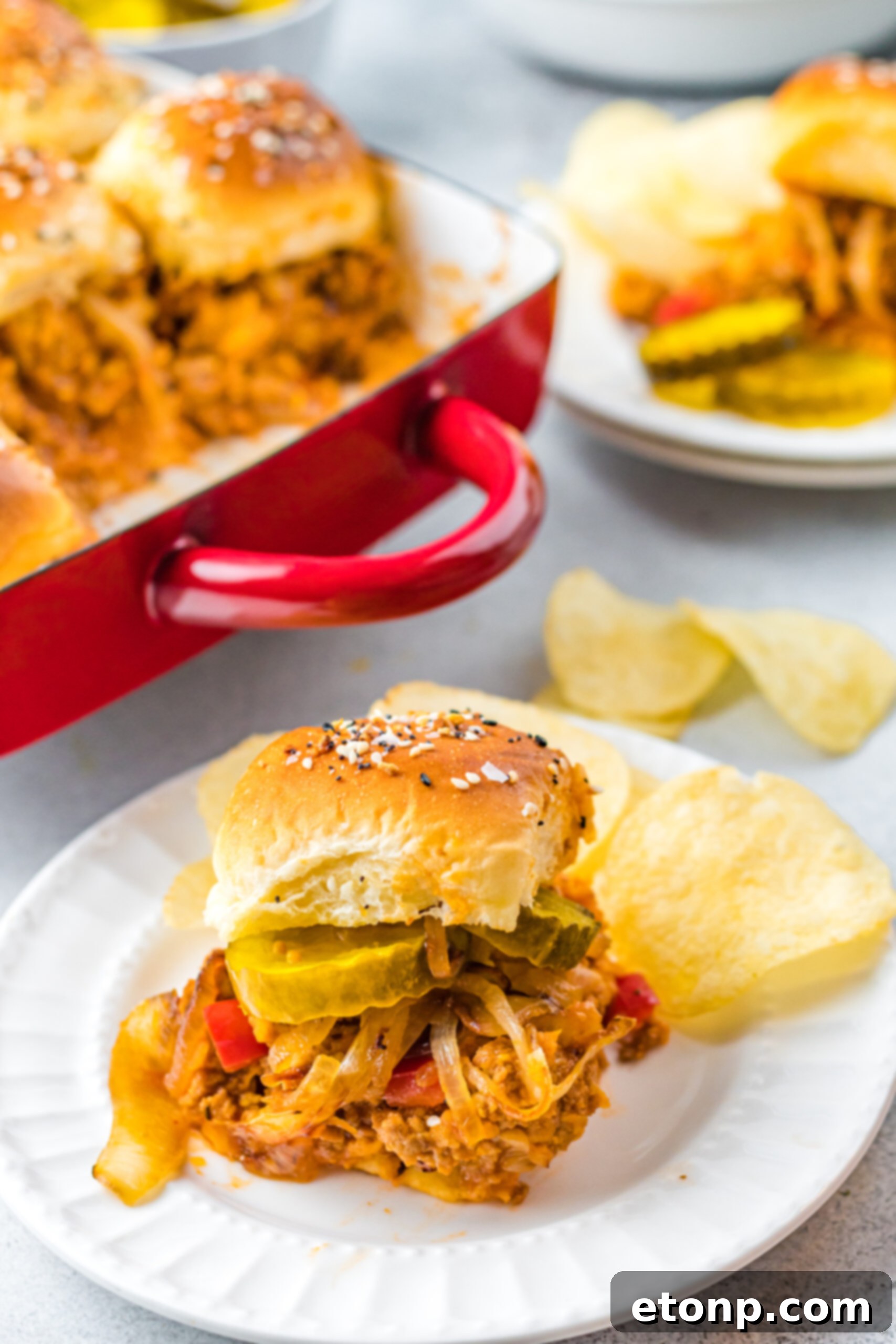 Front view of a Cheesy Chicken Sloppy Joe Slider on a white plate served with chips.
