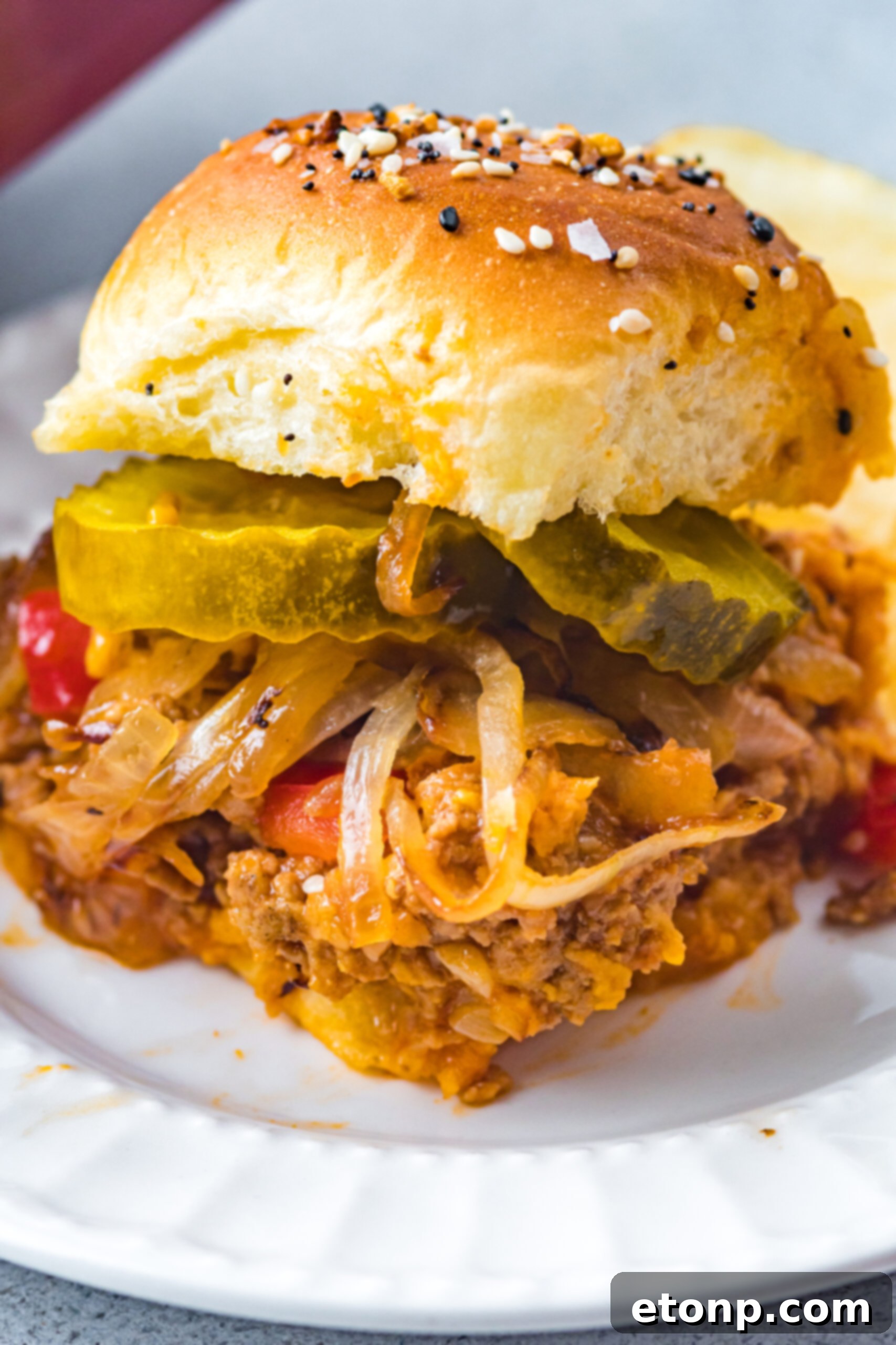Front view of a Cheesy Chicken Sloppy Joe Slider on a white plate.