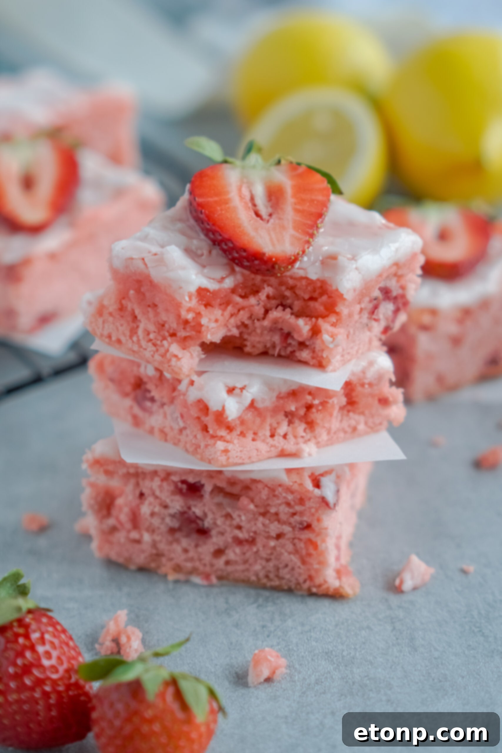 Front view of three Strawberry Lemon Brownies stacked with a bite removed from the top brownie.