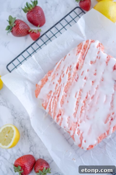 Drizzling lemon glaze over warm strawberry brownies.