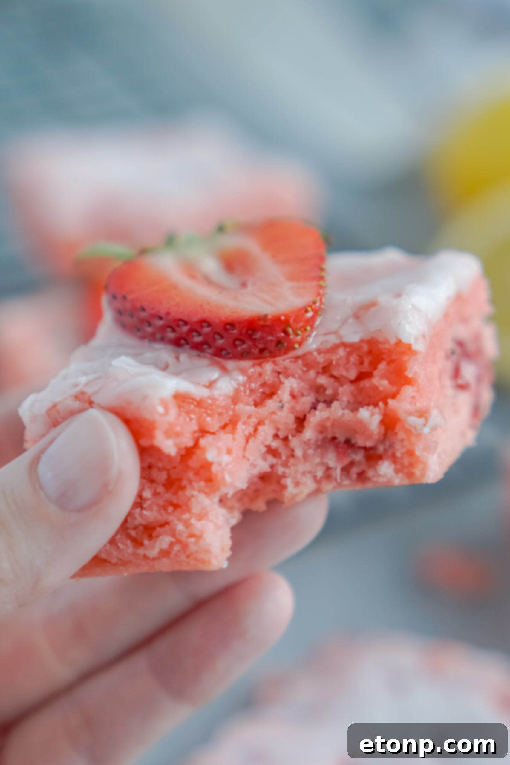 Holding up one of the strawberry brownies with a bite missing 