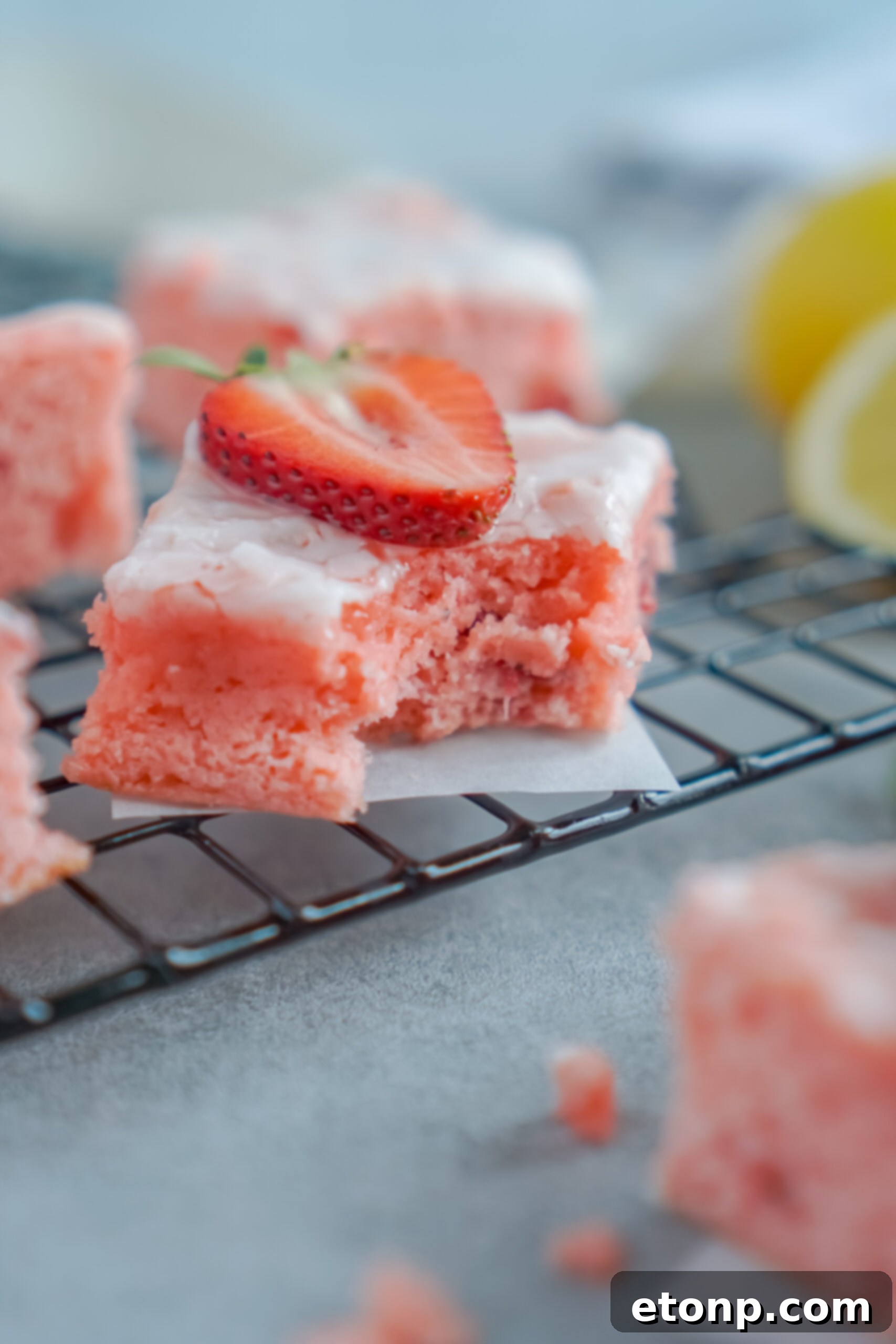 Front view of a Strawberry Lemon Brownie on a black wire rack with a bite removed.