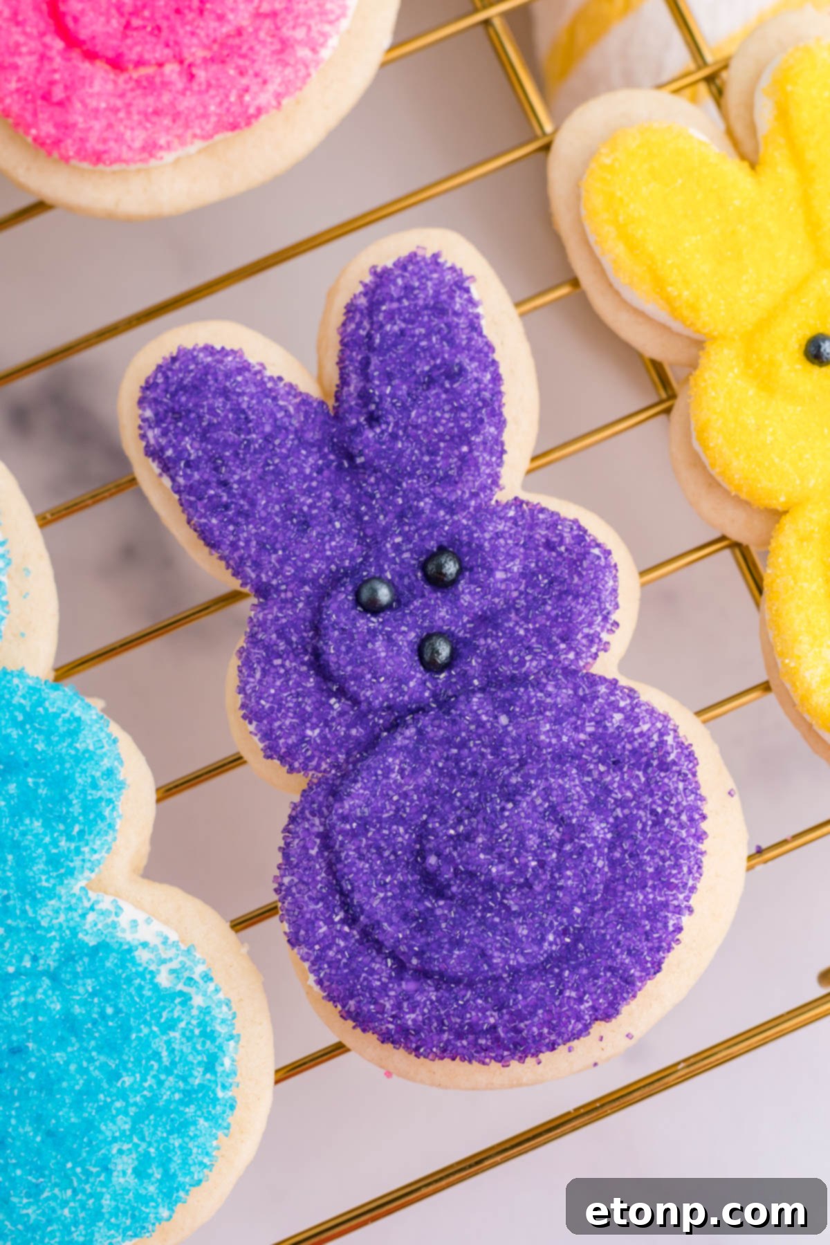 Overhead view of a purple bunny cookie on a gold cooling rack. 