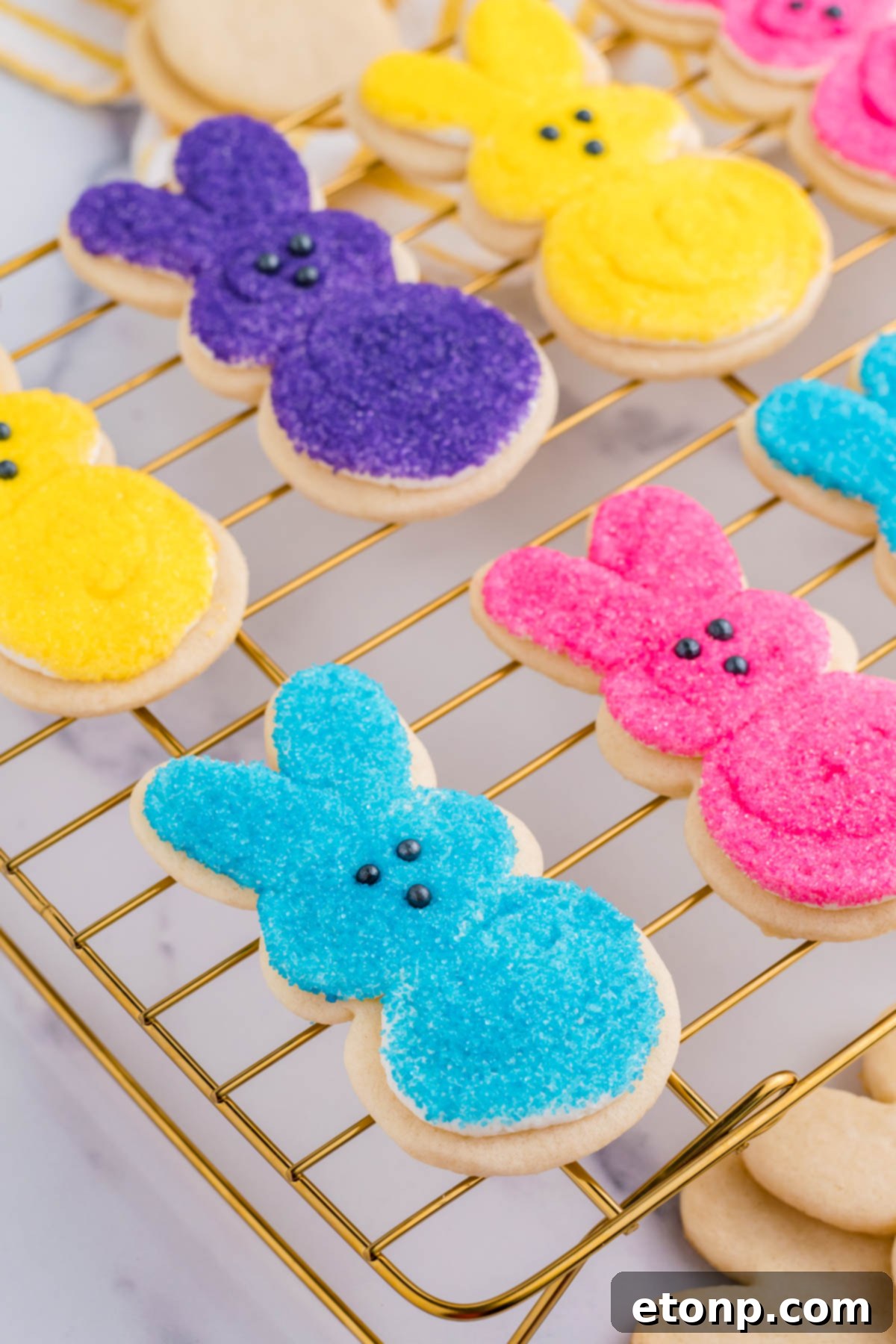 Side view of multicolored Easter Bunny Cookies on a gold cooling rack. 
