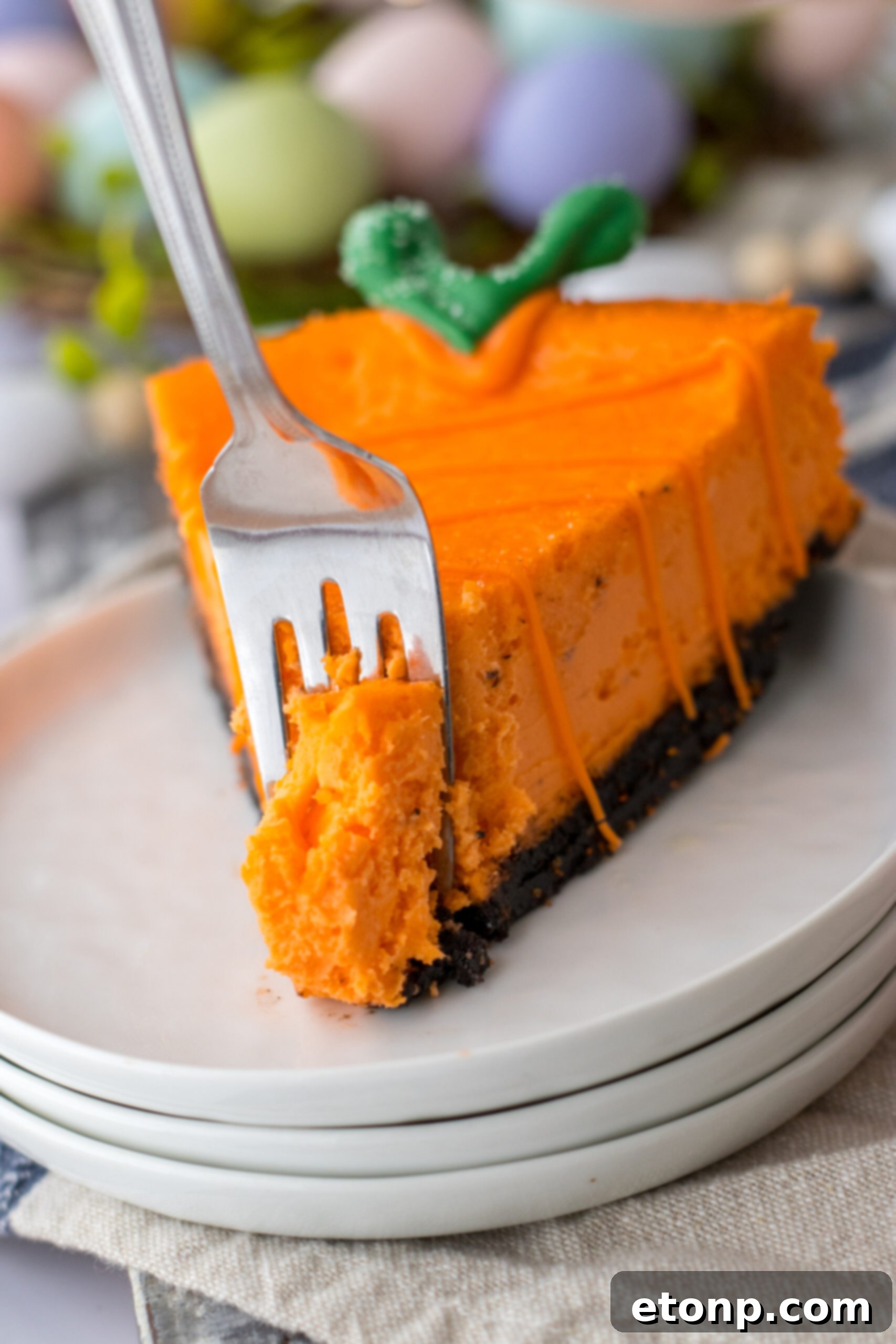 Carrot Cake Cheesecake 15 A cheesecake carrot on a white plate with a silver fork removing a bite.