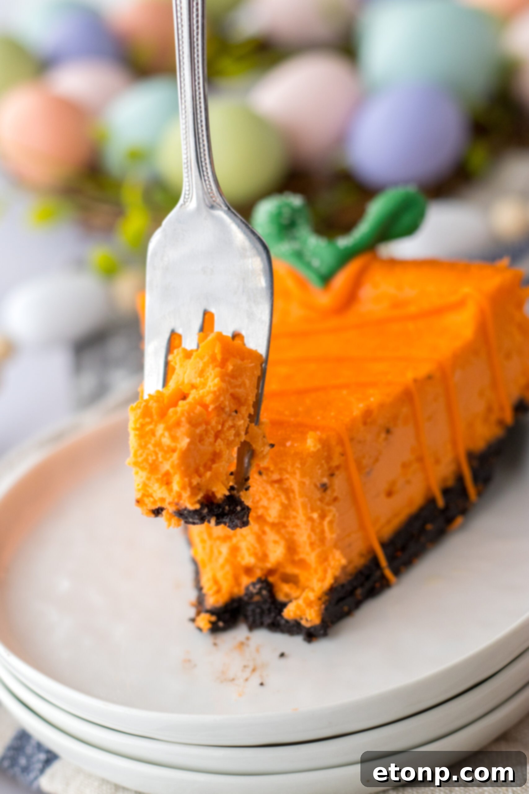 Carrot Cake Cheesecake 17 A cheesecake carrot on a white plate with a silver fork removing a bite.