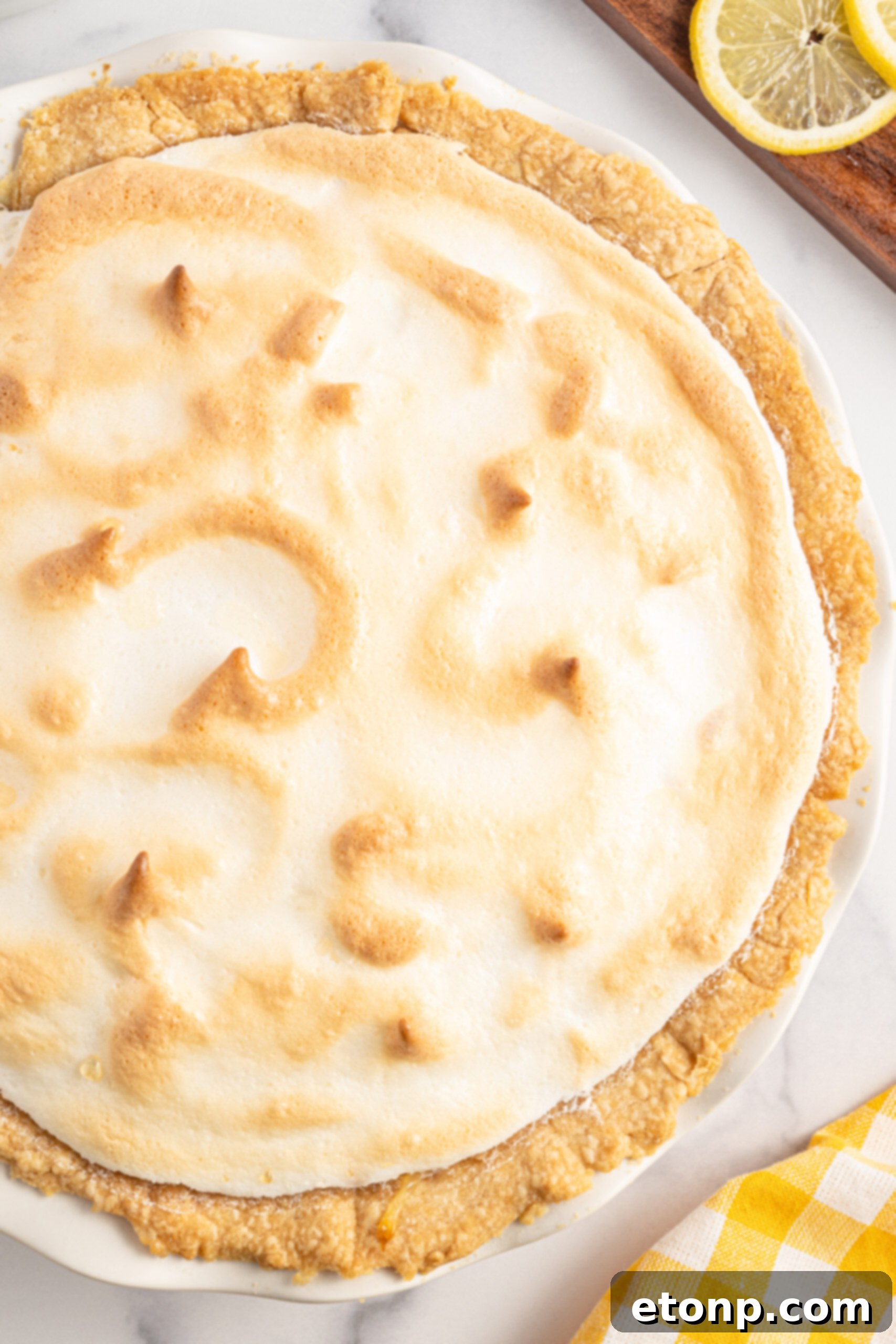 Close-up shot of the perfectly toasted, golden meringue topping on a lemon meringue pie.