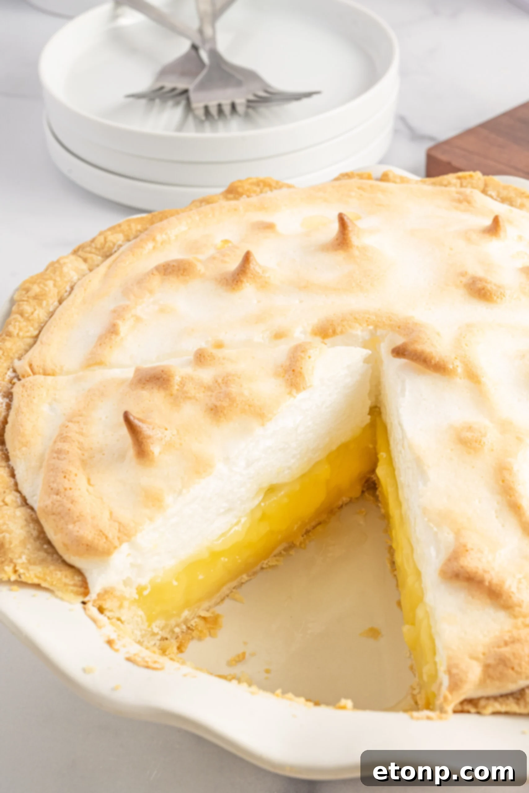 Side view of a perfect slice of lemon meringue pie, emphasizing the height and texture of the meringue and the distinct layers.