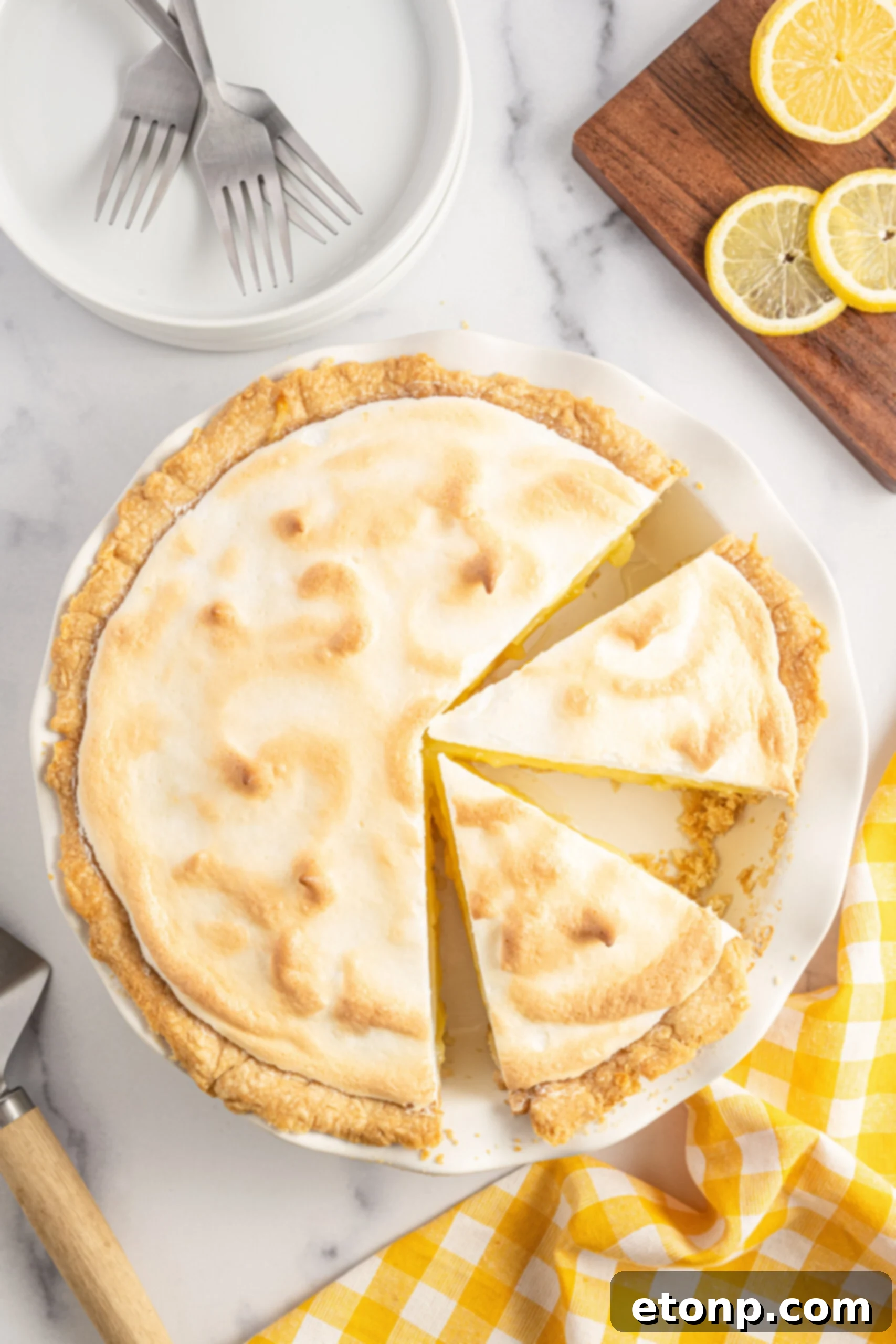 Overhead shot of two inviting slices of lemon meringue pie in a white pie dish, ready to be enjoyed.