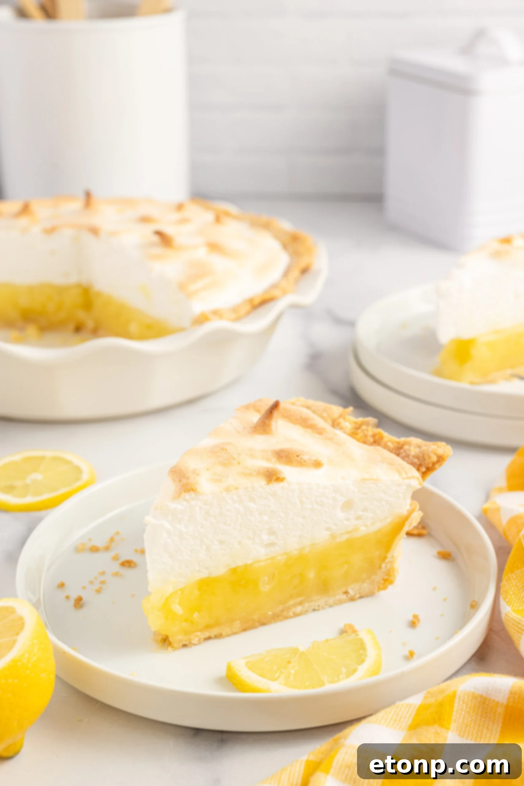 Detailed close-up of a single slice of lemon meringue pie, showcasing the layers and texture of the filling and meringue, with fresh lemon slices.
