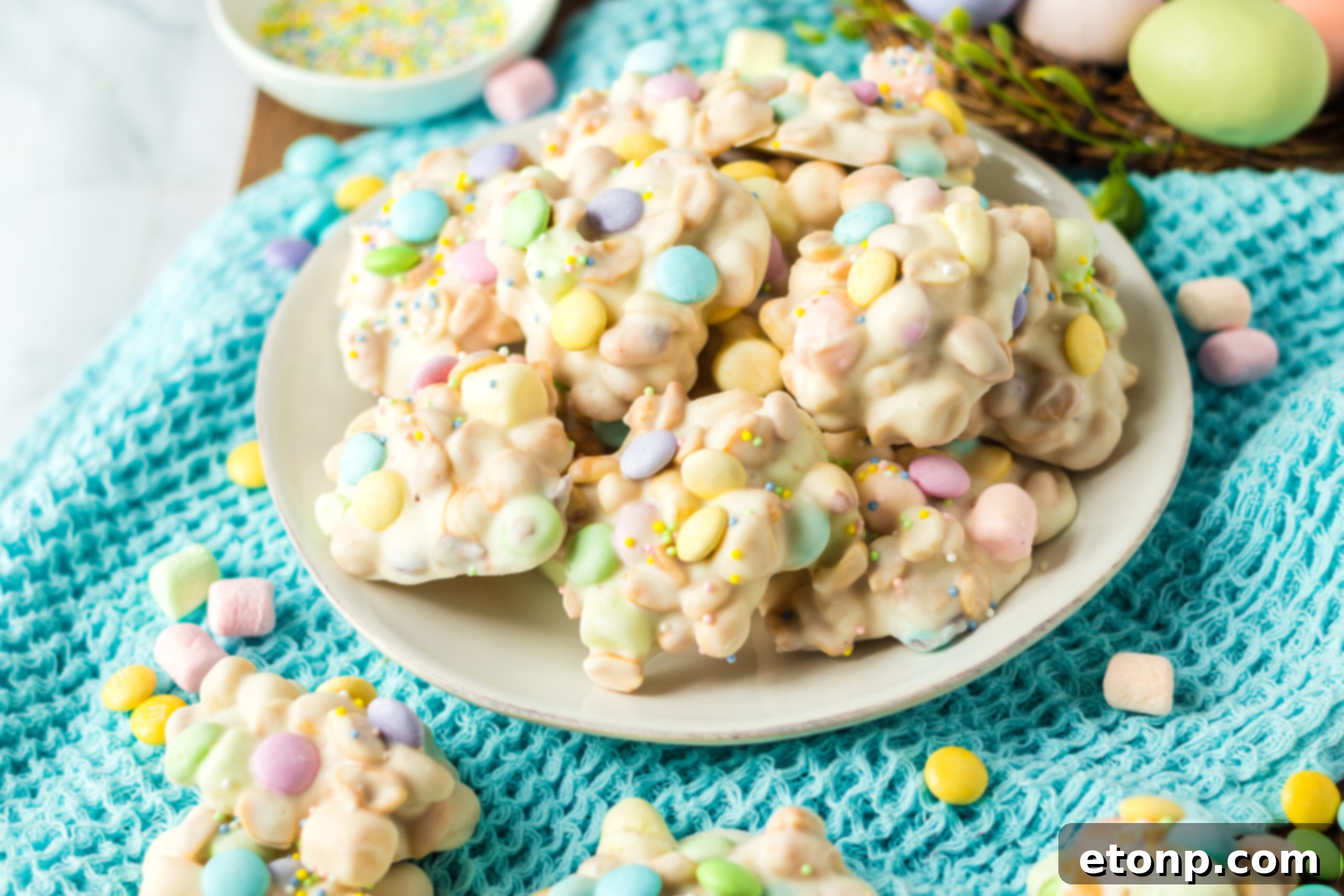 Side view of the stacked candy on a white plate on a teal colored linen.