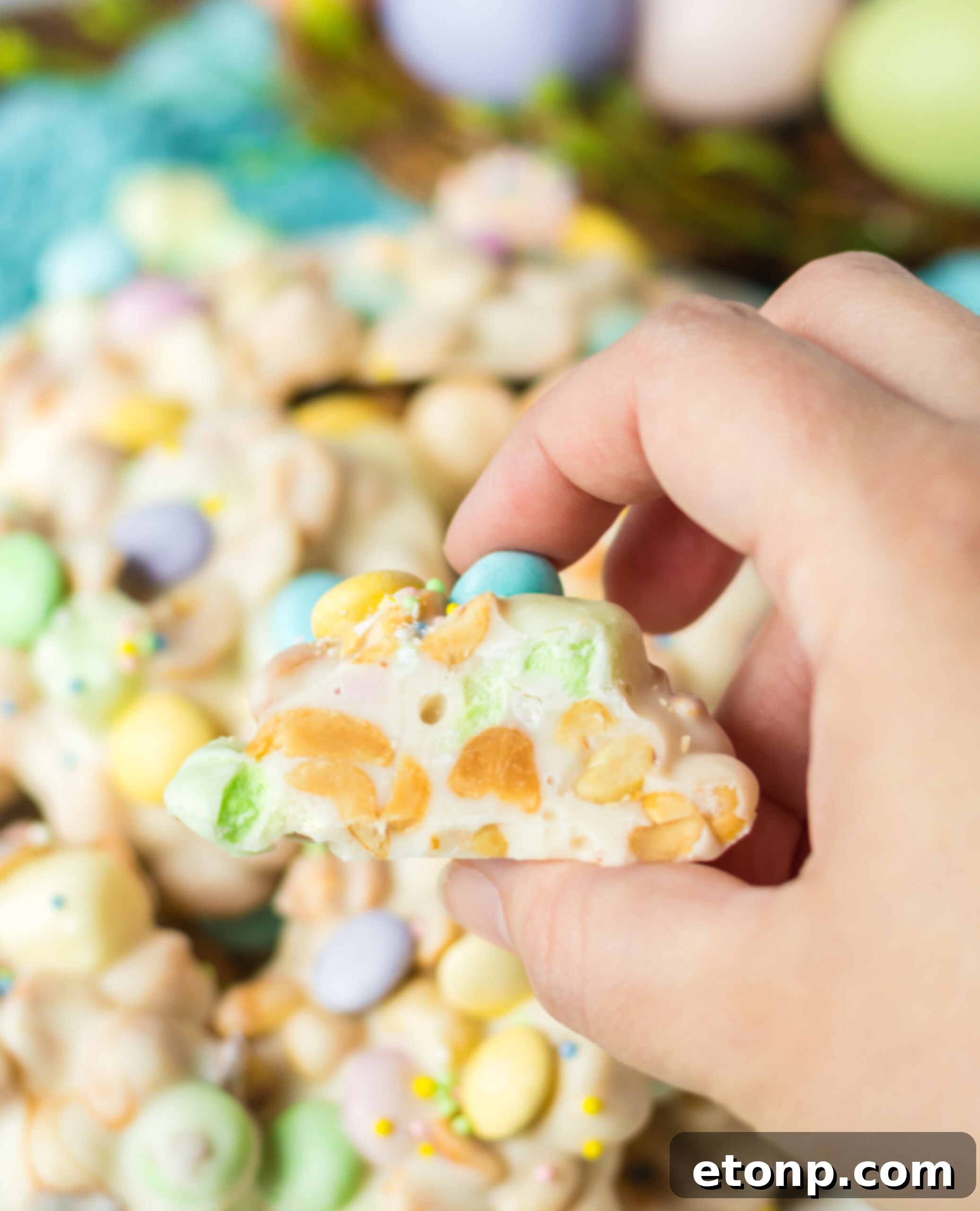 A hand holding a piece of Easter candy with a bite removed. 