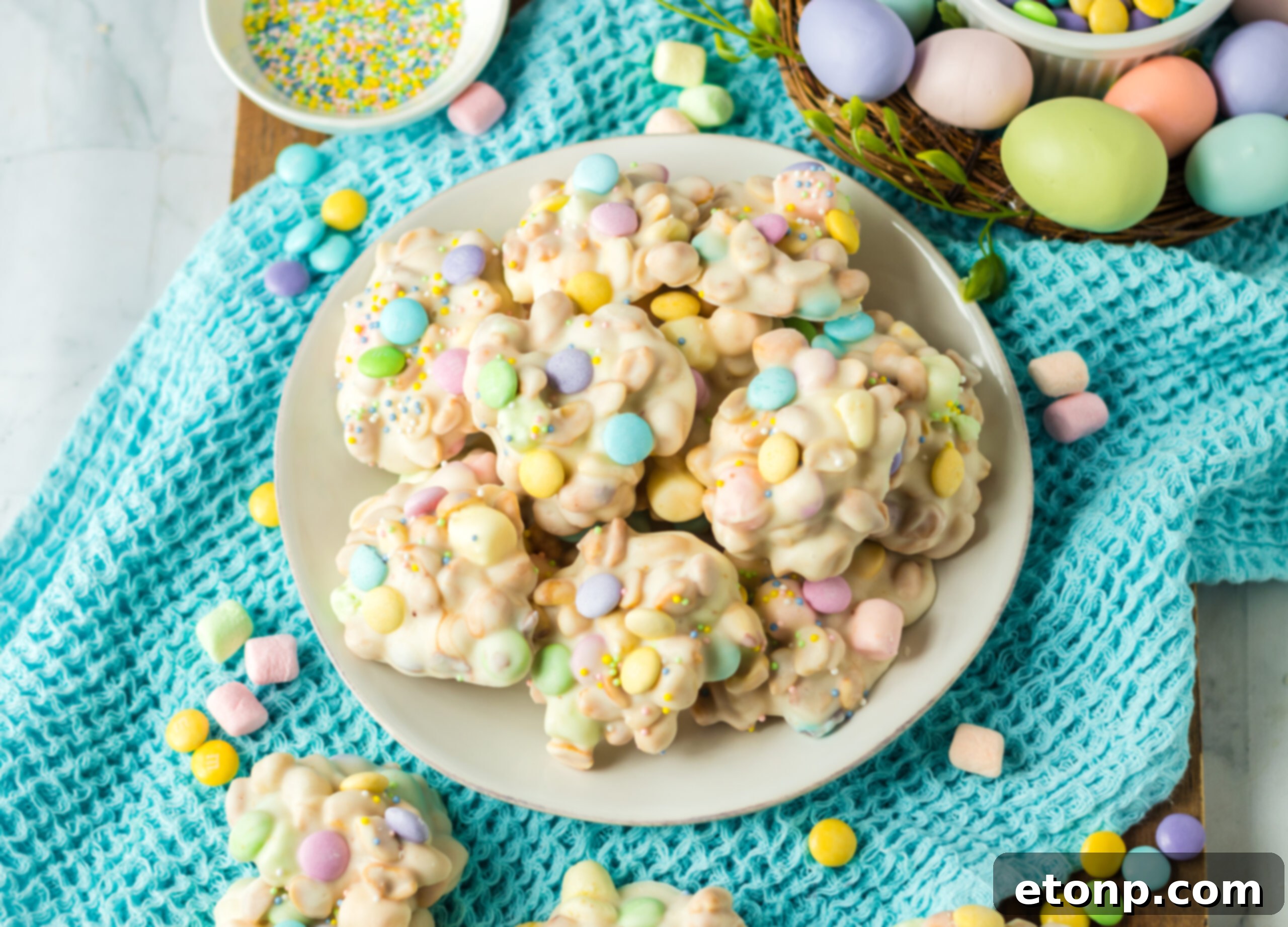 Overhead view of the slow cooker Easter candy on a white plate on a teal linen. 