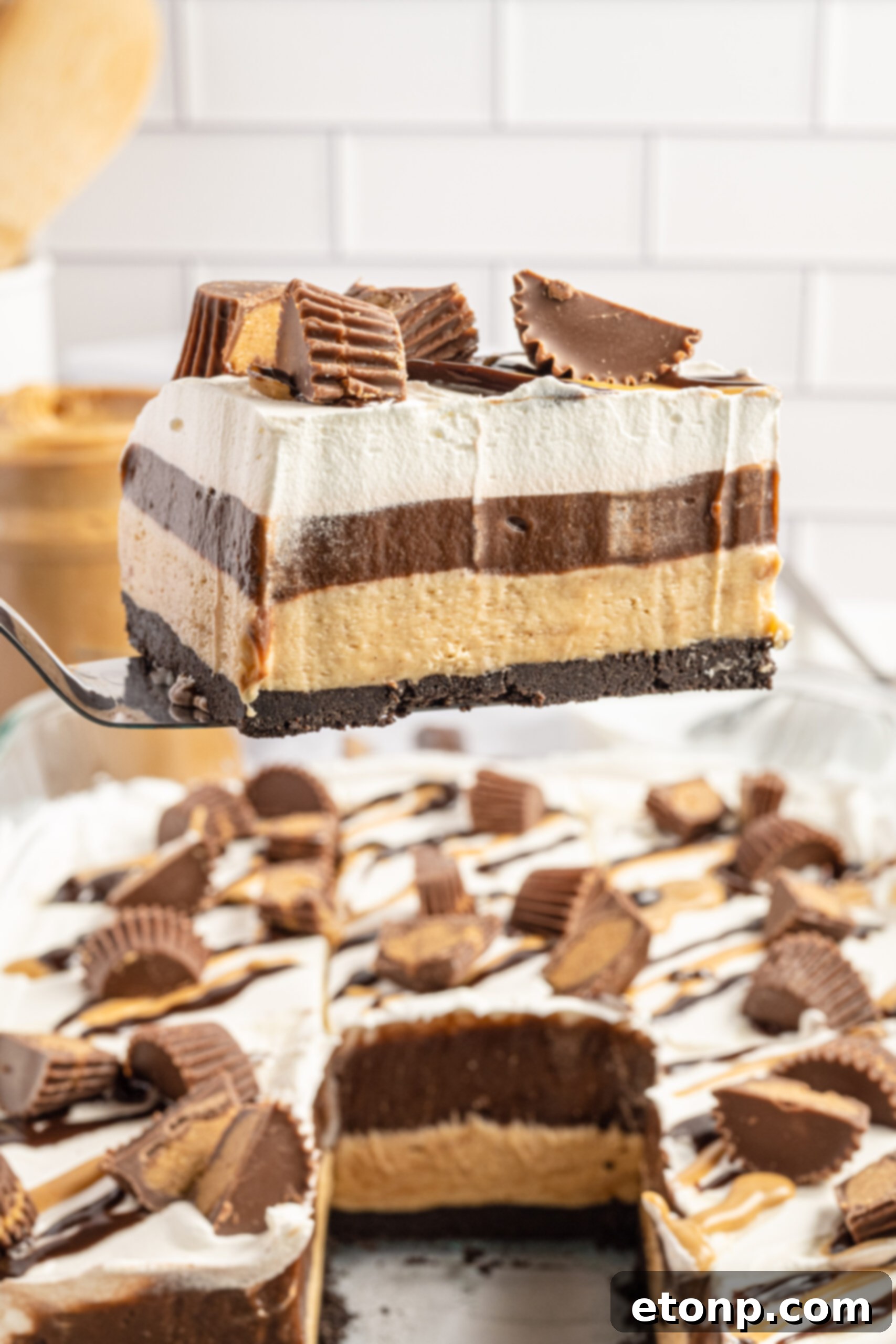 A piece of Reese's chocolate peanut butter cup lasagna being removed from the baking dish with a silver spatula. 