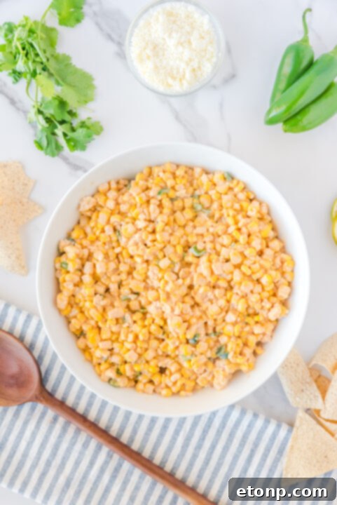 Freshly chopped cilantro and crumbled queso fresco being incorporated into the corn salad.