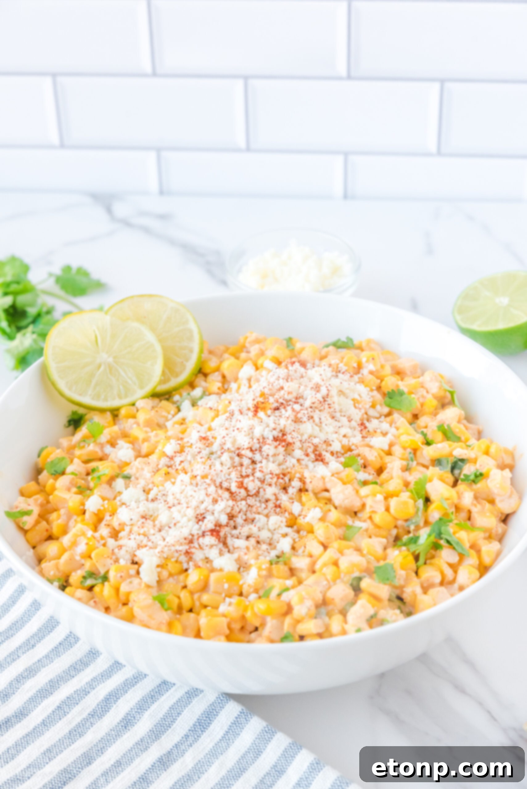 Mexican Street Corn Salad presented in a large white serving bowl, showcasing its creamy texture and colorful ingredients.
