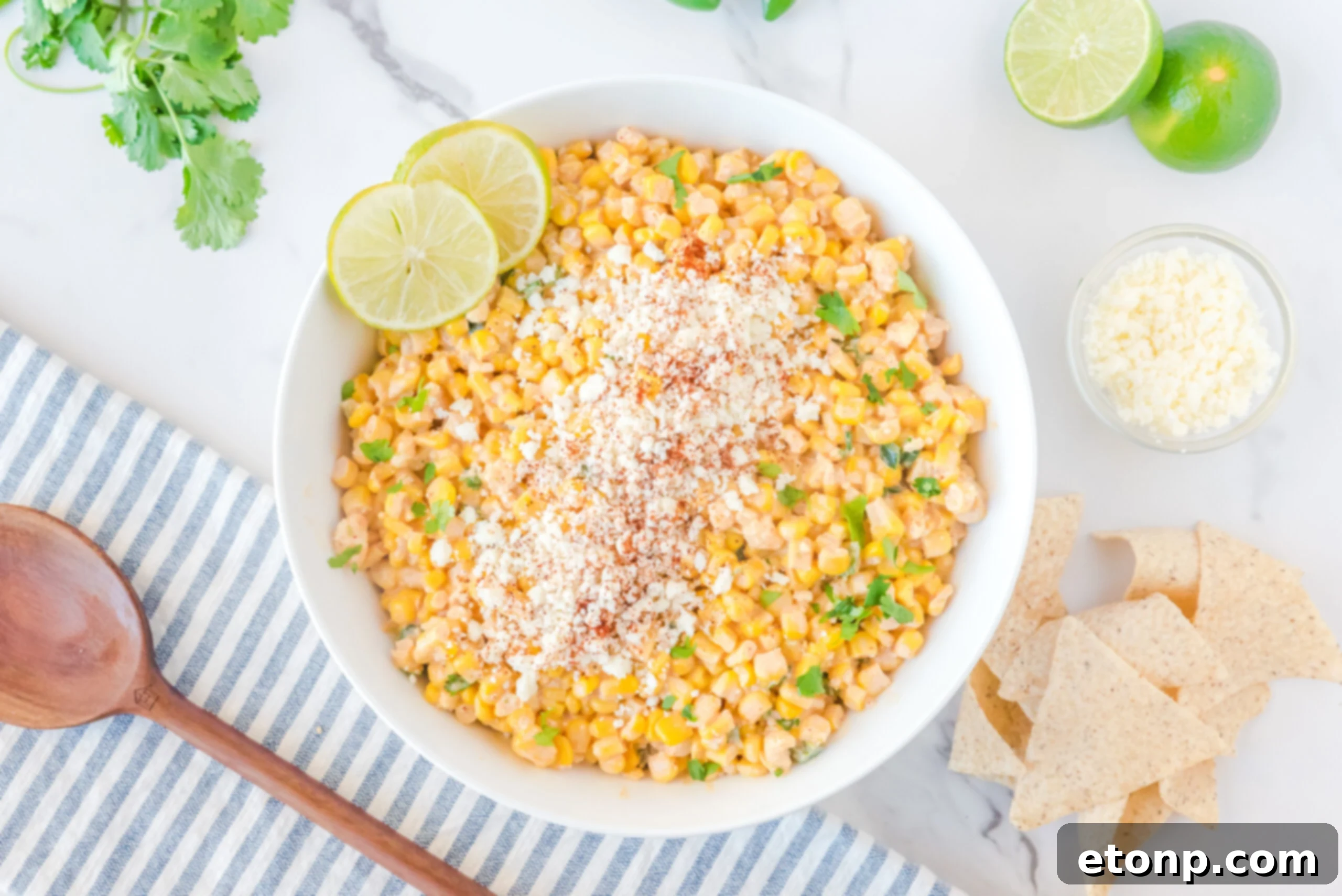 A wide shot of Mexican Street Corn Salad in a large white serving bowl, highlighting its abundant ingredients and vibrant hues.