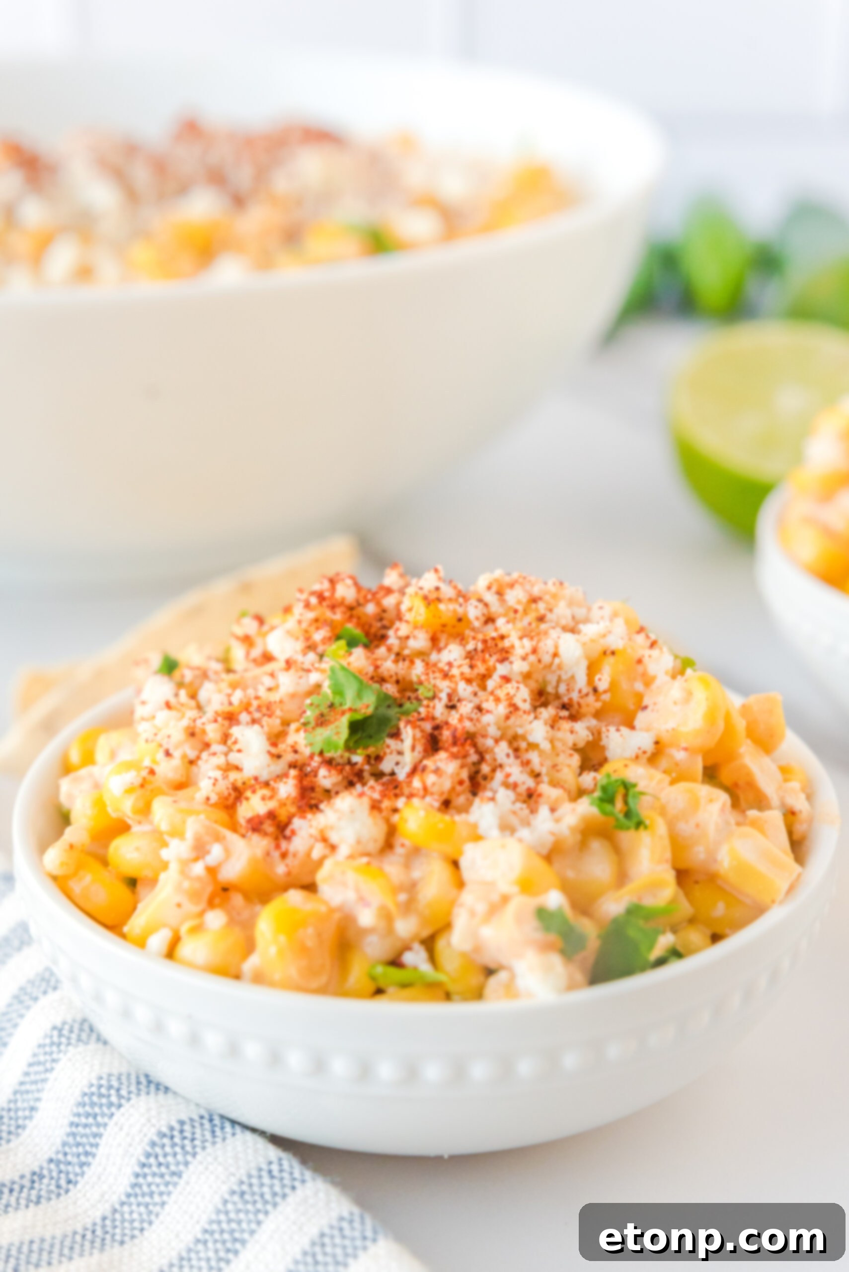 Mexican Street Corn Salad in a clean white bowl, garnished with a vibrant sprinkle of paprika and fresh queso fresco crumbles.