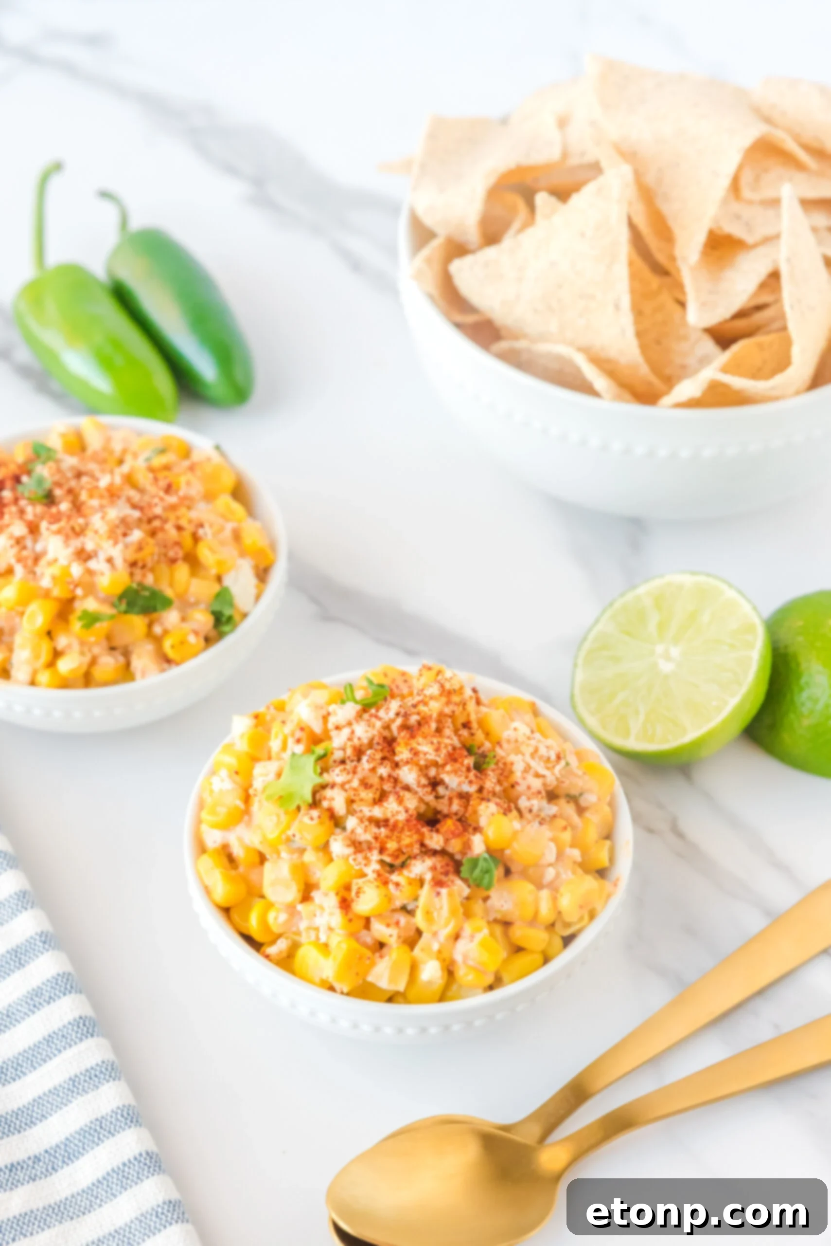 Mexican Street Corn Salad elegantly presented in two small white bowls, generously garnished with paprika and fresh queso fresco.