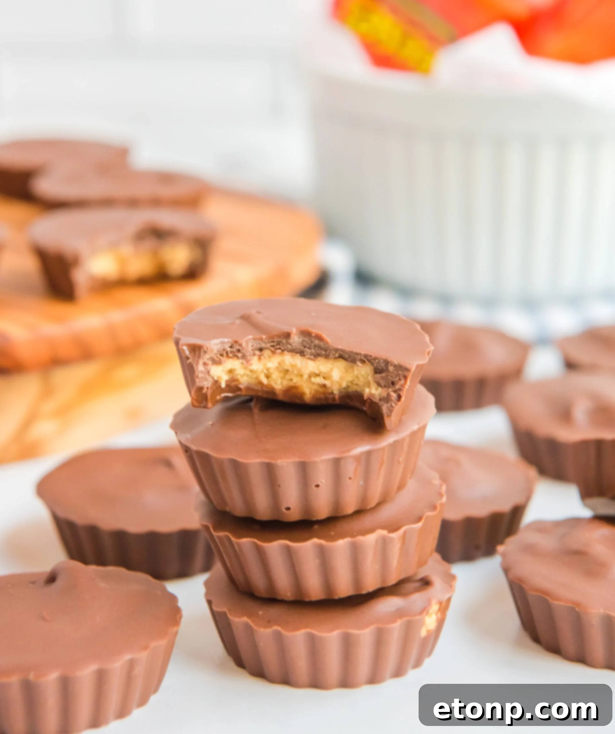 Homemade Peanut Butter Chocolate Cups 2 A stack of golden-brown homemade peanut butter cups with a bite taken from the top one, revealing the creamy peanut butter filling inside.