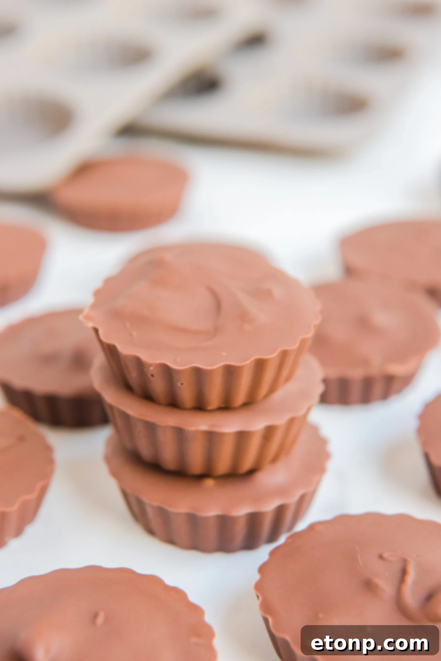 Homemade Peanut Butter Chocolate Cups 13 A trio of homemade Reese's Peanut Butter Cups stacked on a white background, highlighting their smooth chocolate and inviting appearance.