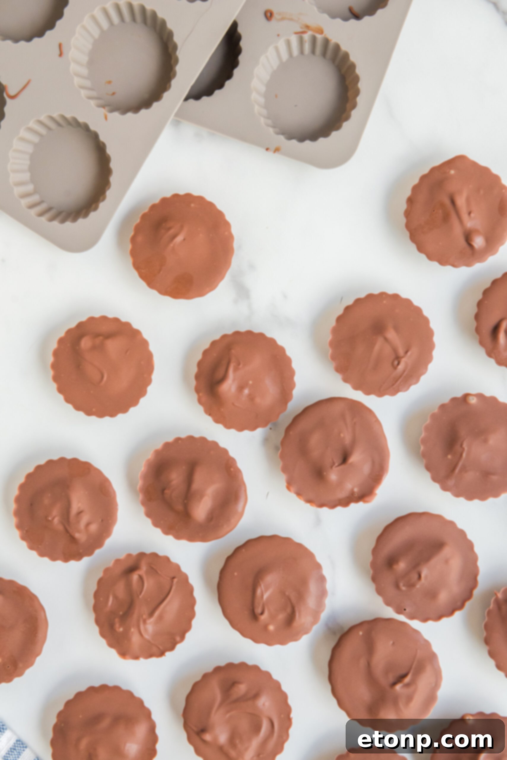 Homemade Peanut Butter Chocolate Cups 15 An inviting overhead view of several homemade Reese's Peanut Butter Cups arranged neatly, highlighting their perfect round shape and smooth chocolate surface.