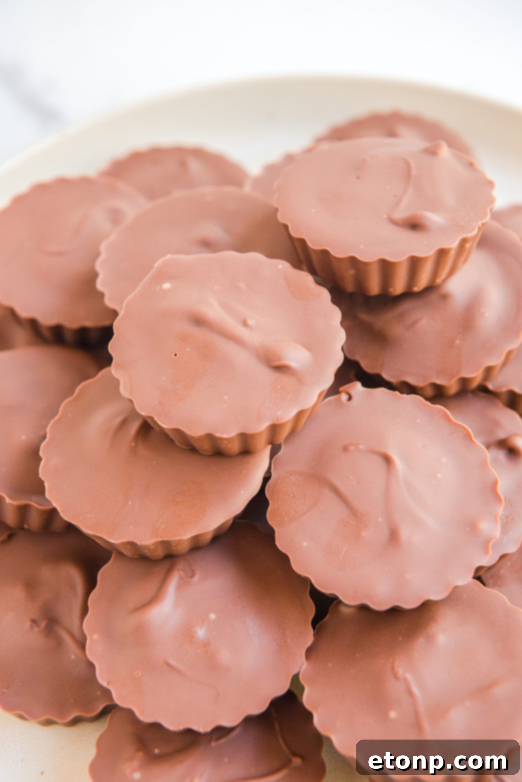 Homemade Peanut Butter Chocolate Cups 16 Several homemade Reese's Peanut Butter Cups elegantly presented on a pristine white serving plate, ready to be enjoyed.
