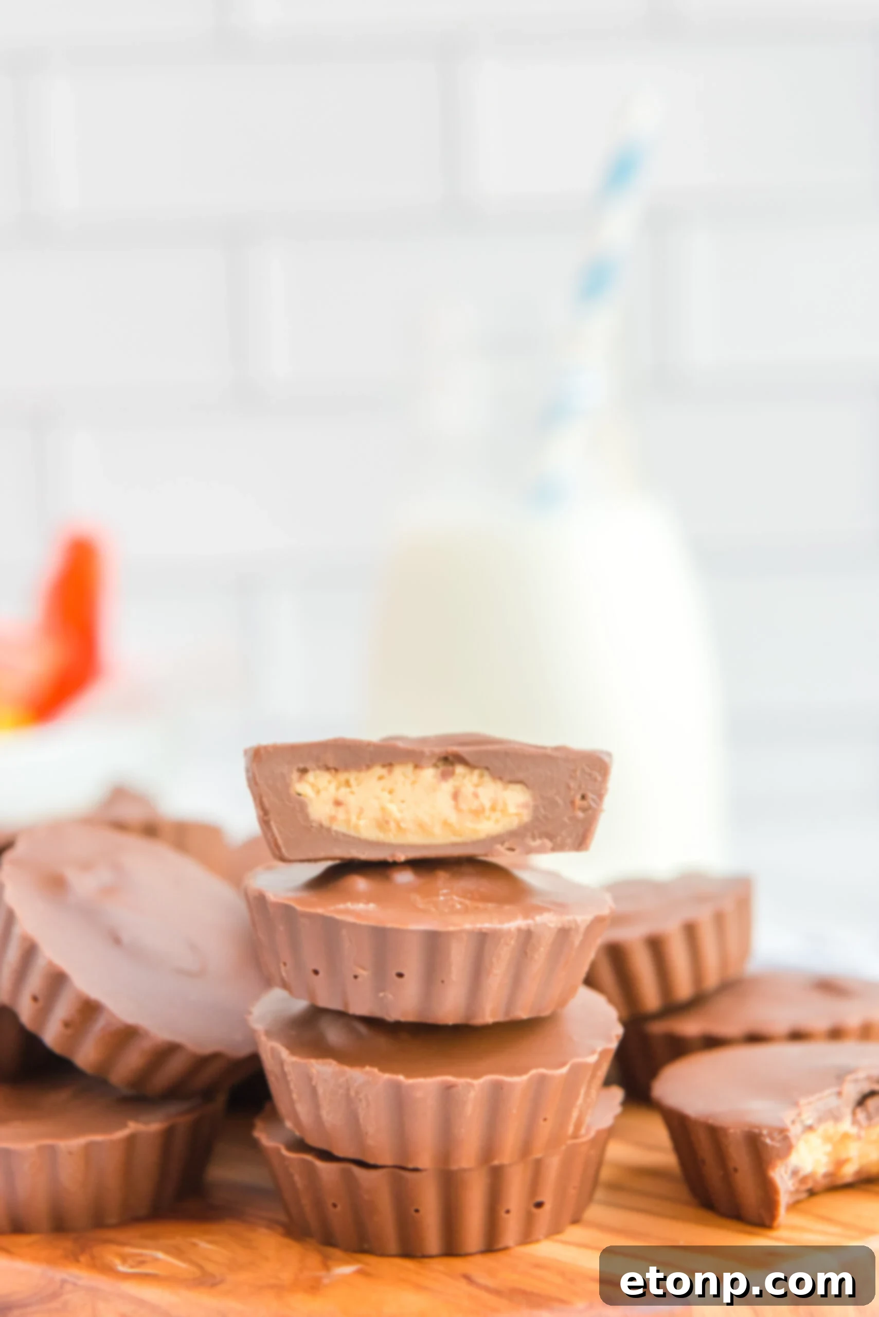 Homemade Peanut Butter Chocolate Cups 19 A stack of four perfectly formed homemade Reese's Peanut Butter Cups on a rustic wooden board, enticingly displaying their rich texture and filling.