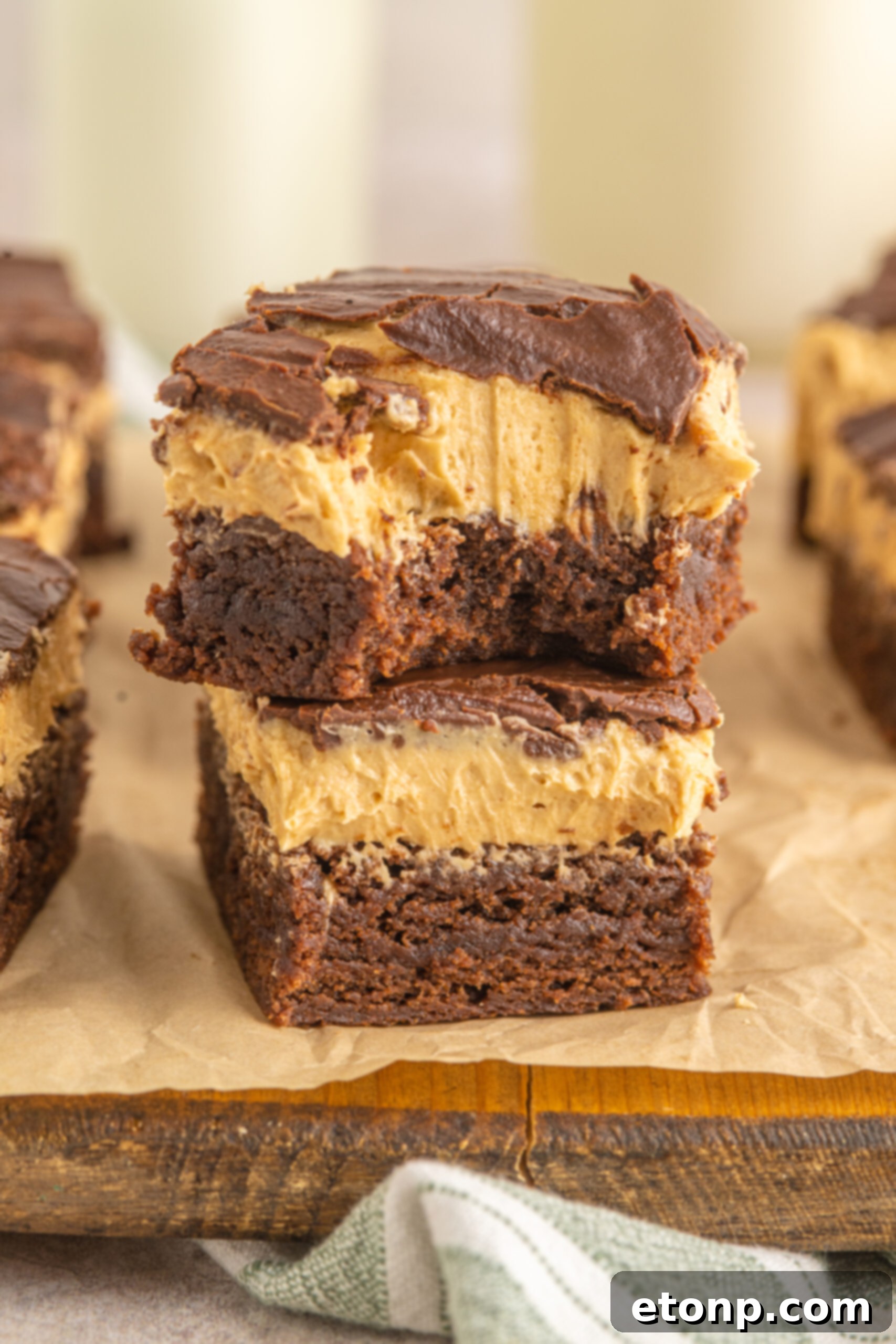 Two Buckeye Brownies stacked on top of each other with a bite removed from the top one. 