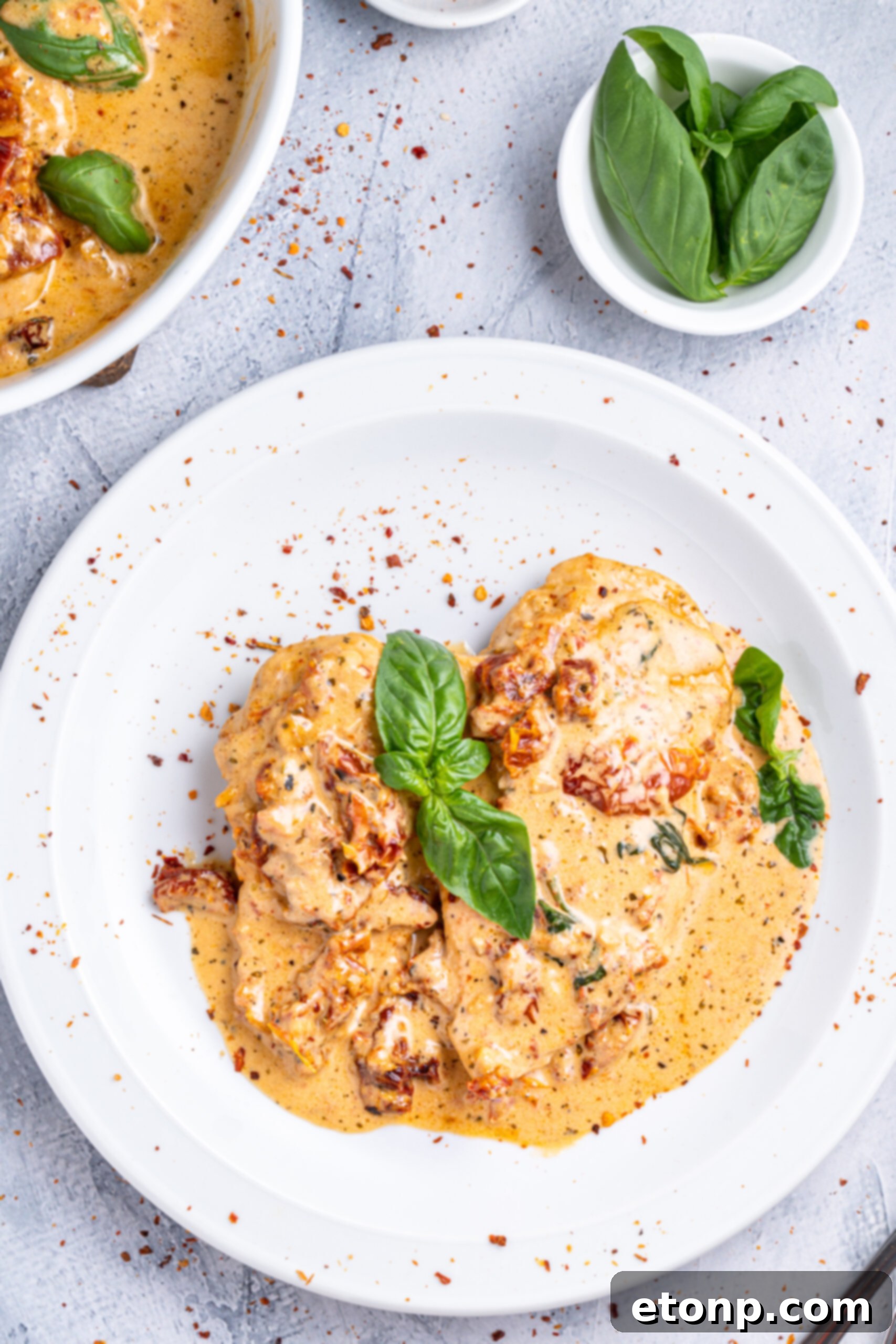 Heart-Winning Chicken 12 Marry Me chicken on a white plate, garnished with fresh basil and red pepper flakes, ready to be enjoyed.