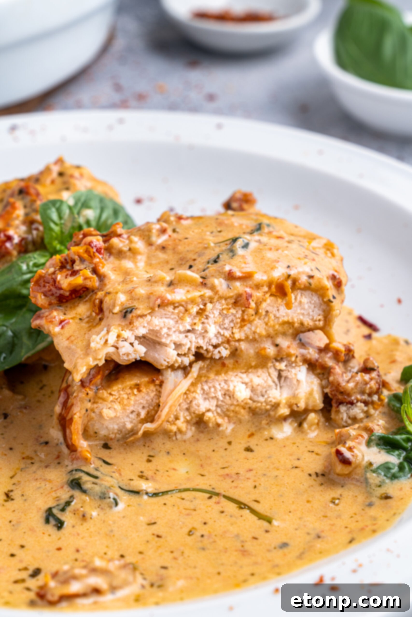 Heart-Winning Chicken 14 Marry Me chicken fillets cut in half and stacked on a white plate, displaying tenderness.