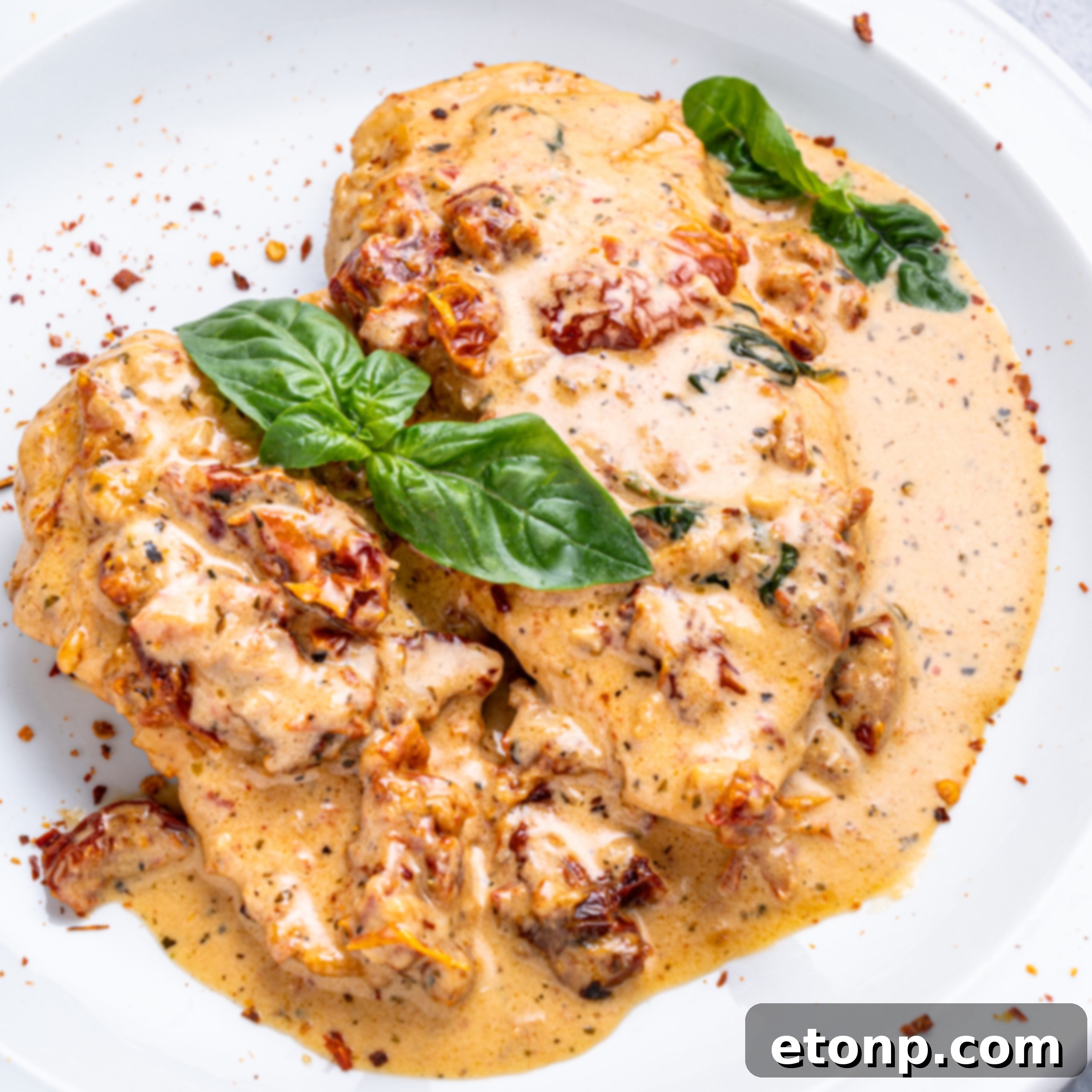 Heart-Winning Chicken 4 Plated Marry Me Chicken on a white plate, garnished with fresh basil and red pepper flakes.