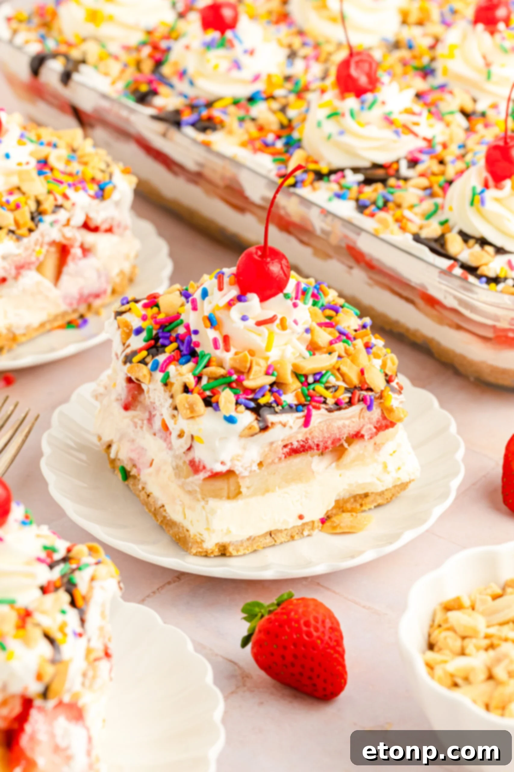 No-Bake Banana Split Bliss 16 Front view of a beautiful slice of No Bake Banana Split Cake on a white plate.