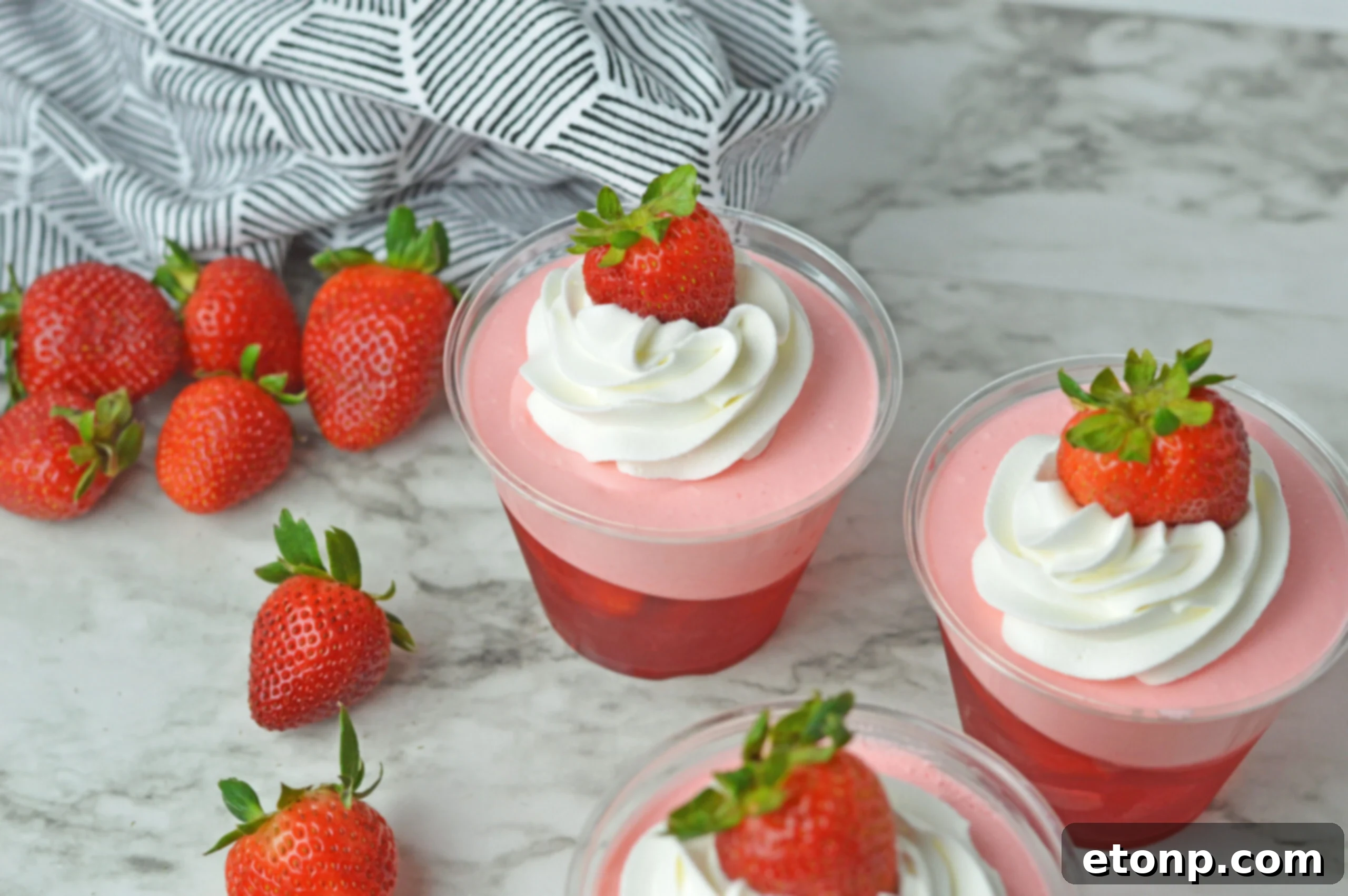 Strawberry Dream Parfaits 14 Overhead view of Strawberry Jello Parfait in plastic cups topped with whipped cream and a strawberry.