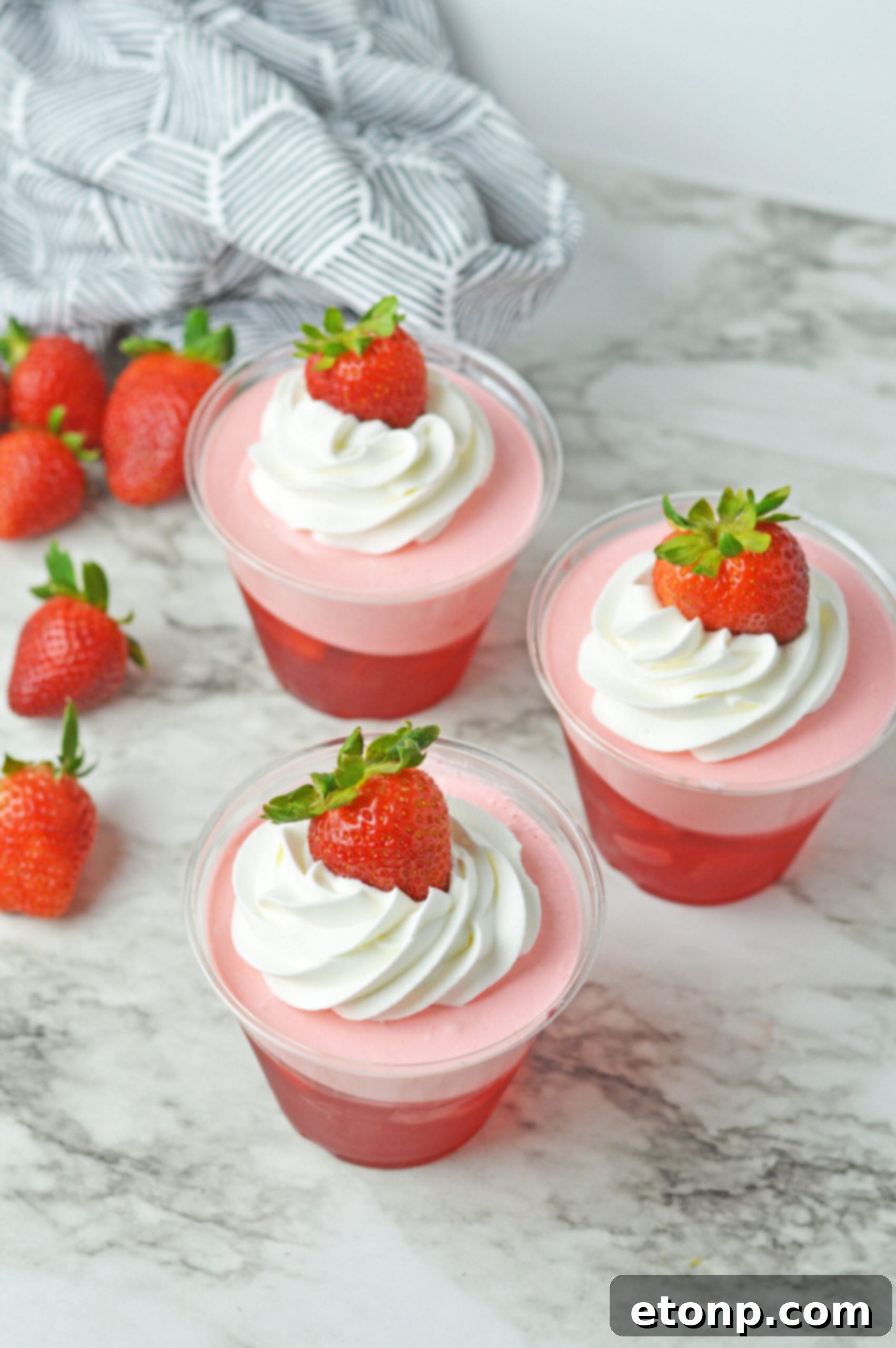 Strawberry Dream Parfaits 15 Overhead view of Strawberry Jello Parfait in plastic cups topped with whipped cream and a strawberry.