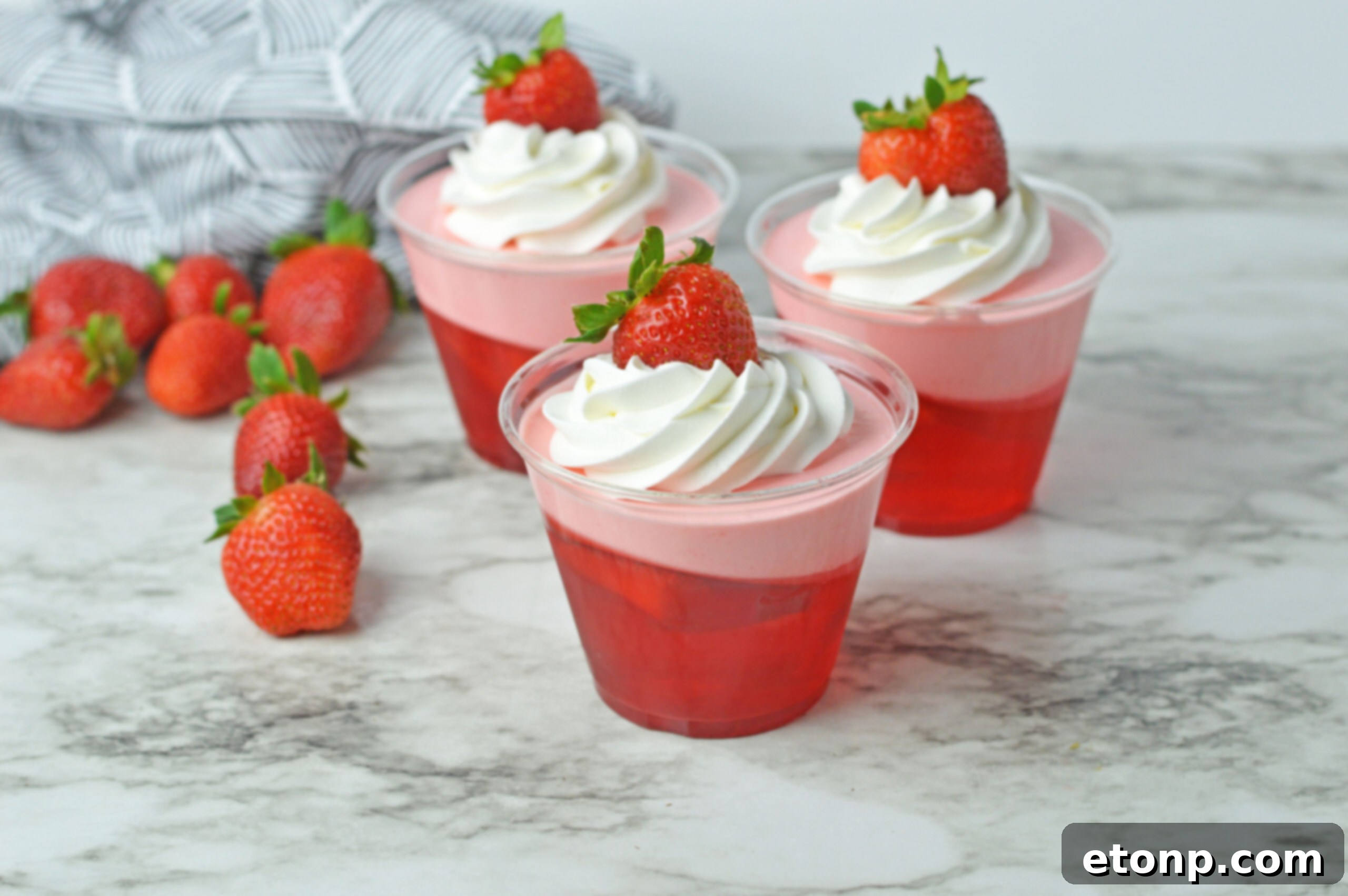 Strawberry Dream Parfaits 16 Front view of Strawberry Jello Parfait in plastic cups topped with whipped cream and a strawberry.