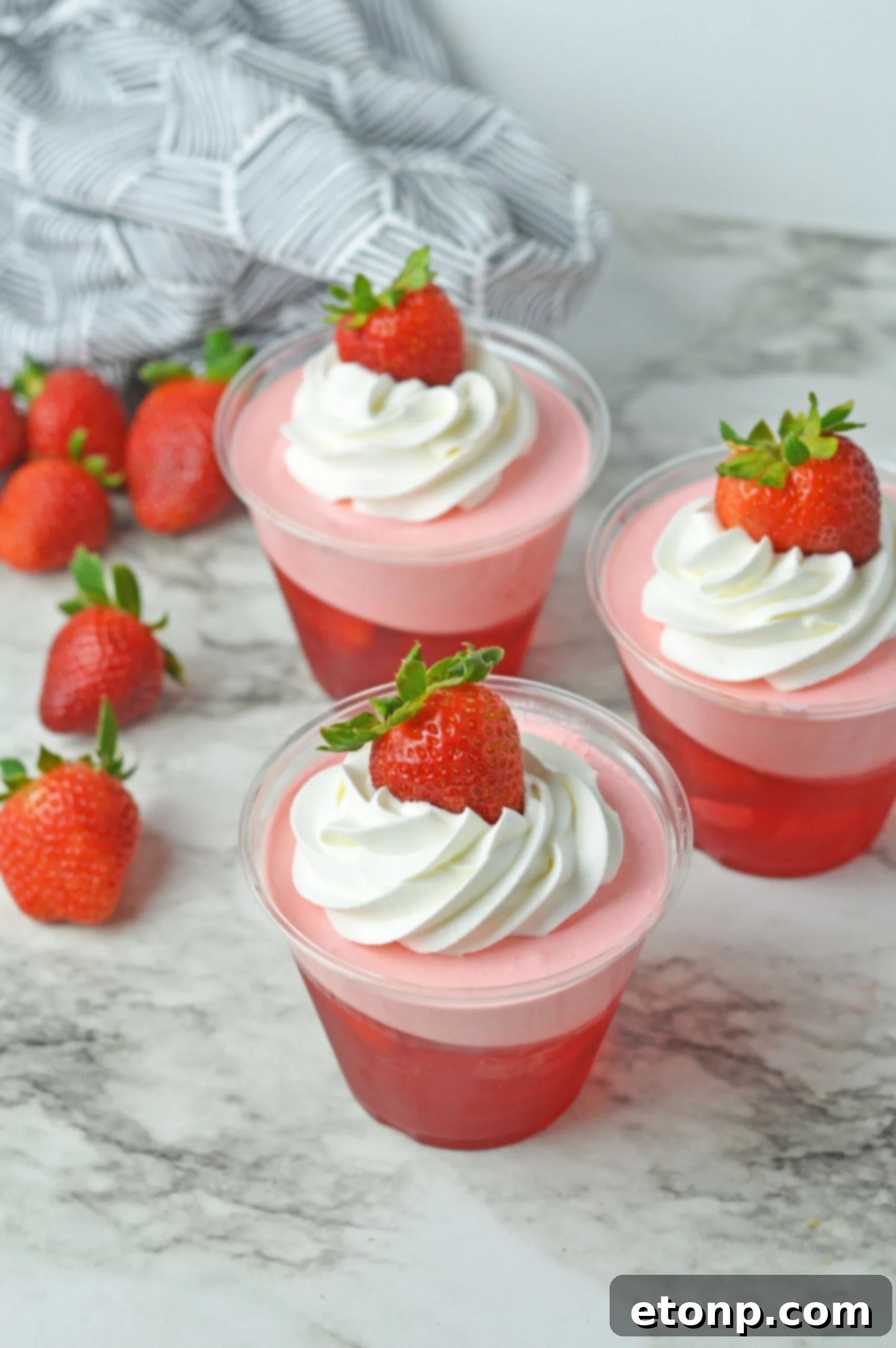 Strawberry Dream Parfaits 3 Front view of Strawberry Jello Parfait in plastic cups topped with whipped cream and a strawberry.