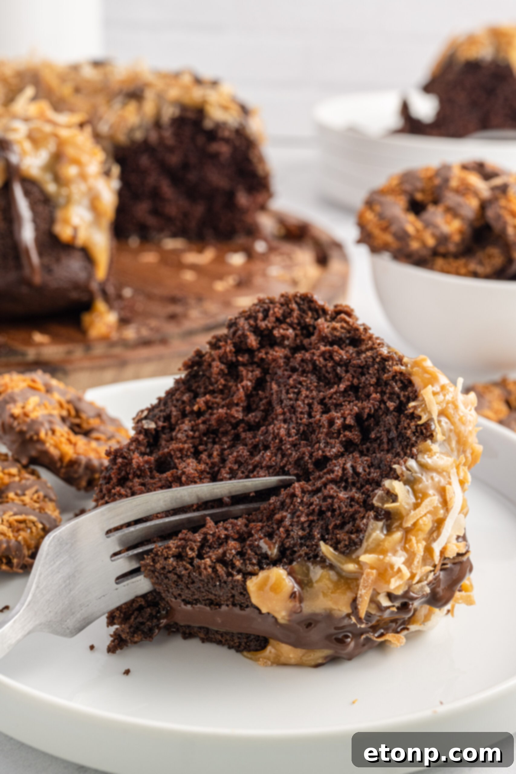 Front view of a silver fork elegantly removing a perfect bite from a slice of Samoa Cake, showcasing the tender crumb and sticky topping, hinting at a Samoa Poke Cake's texture.