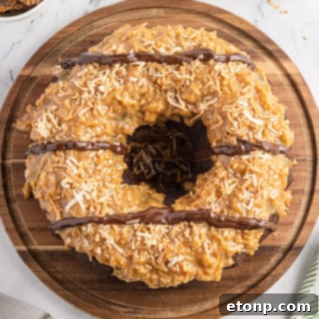 A delicious Samoa Cake, beautifully adorned with golden caramel, abundant toasted coconut, and an elegant chocolate drizzle, ready to be served.