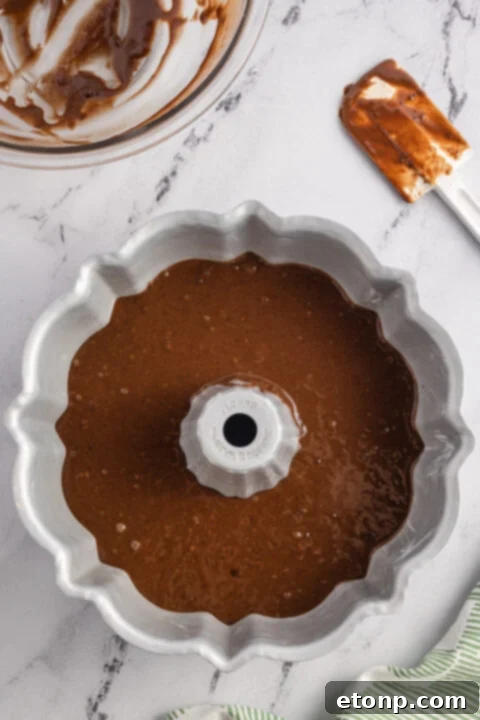 Mixing wet ingredients, including canola oil and sugar, in a separate bowl until light and fluffy for the Samoa cake.