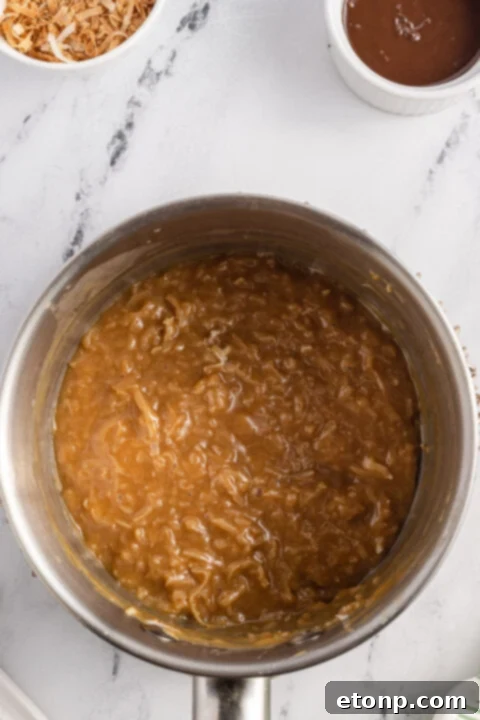 Pouring hot water into the thick Samoa cake batter, a crucial step for achieving ultimate moisture and blooming cocoa flavor.