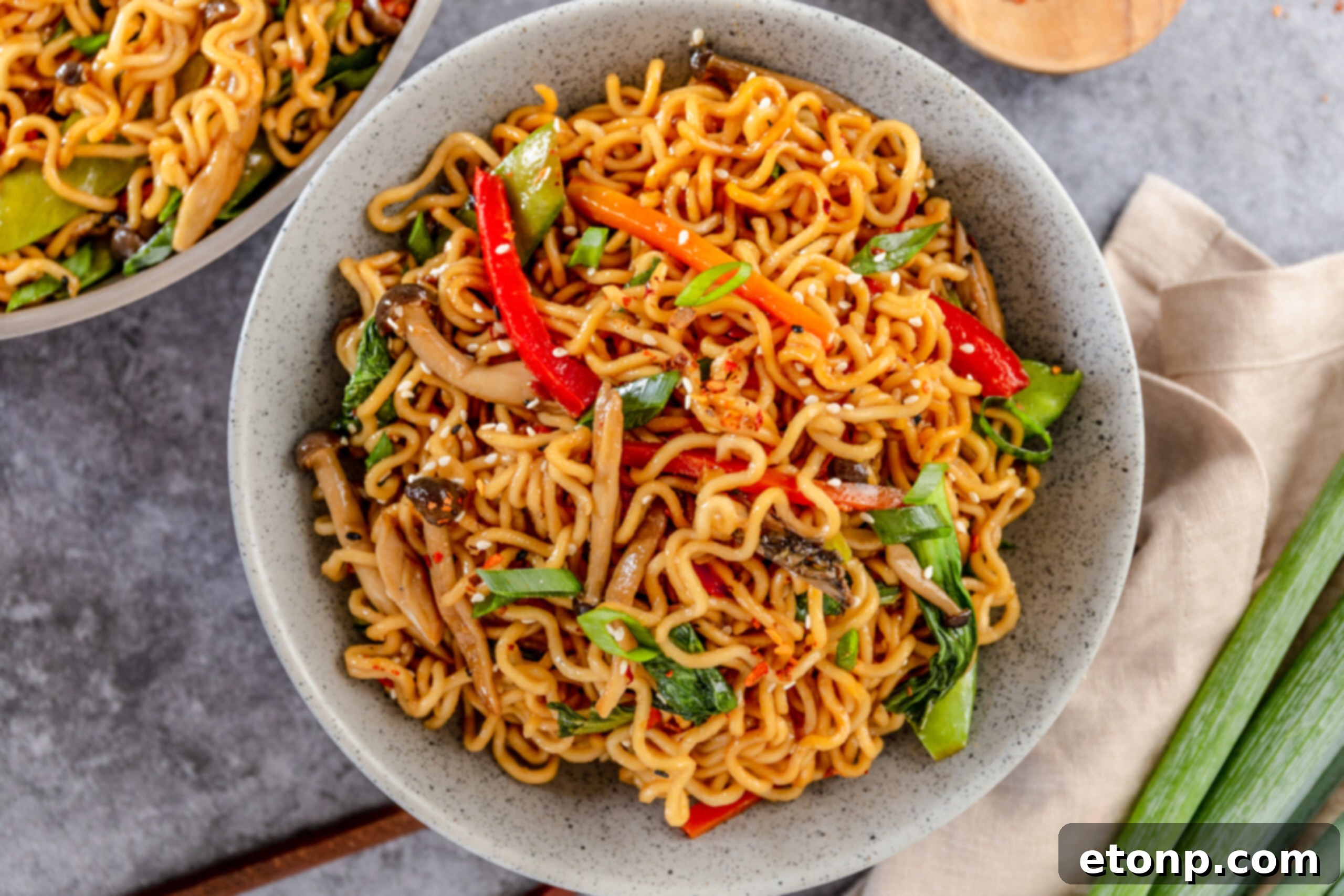A speckled white bowl brimming with Ramen Stir Fry, showing the rich colors and textures of the ingredients.