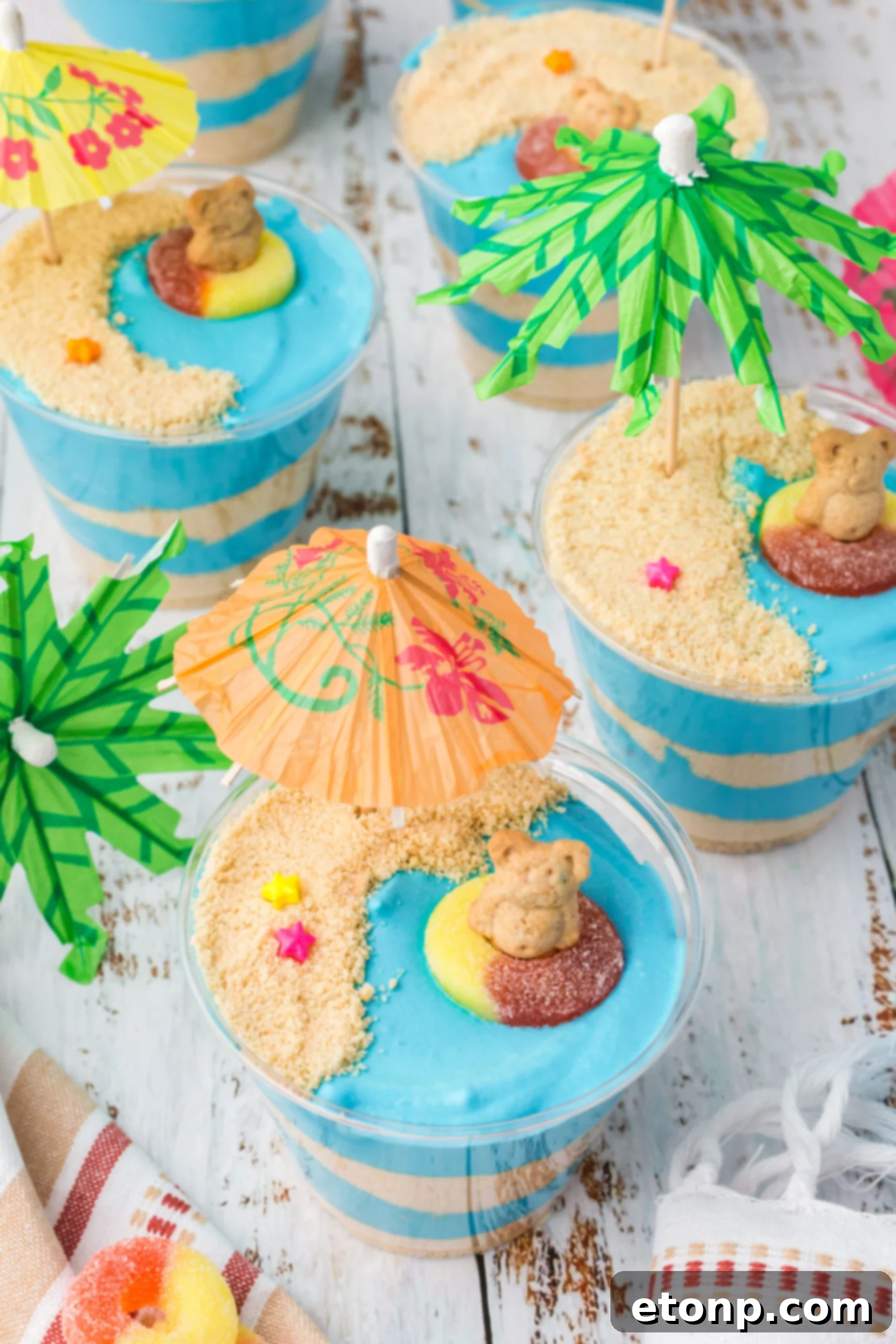 Overhead view of Beach Cheesecake Pudding Cups with small umbrellas and gummy rings, ready to be served.
